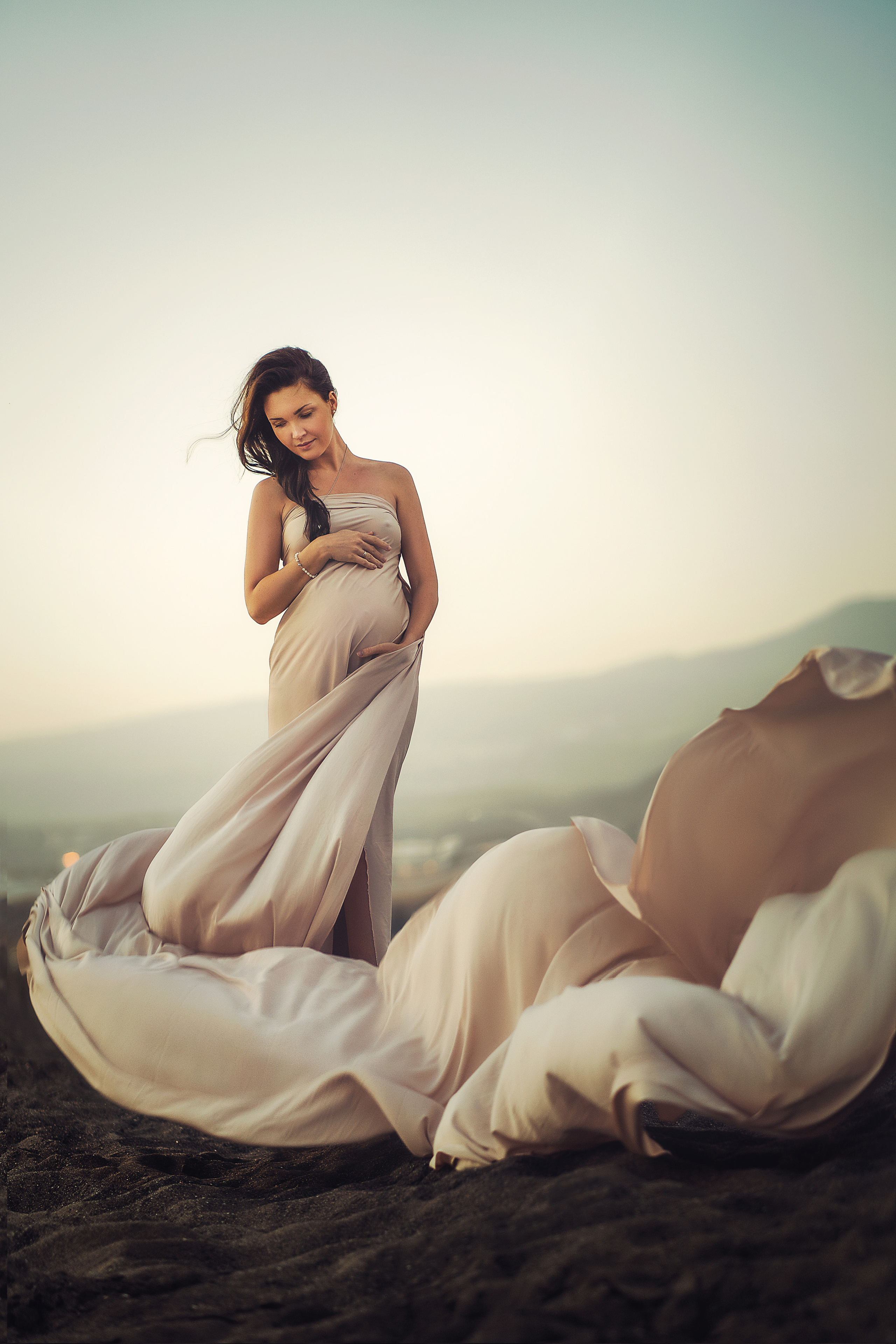 A pregnant girl with a long beige fabric around her