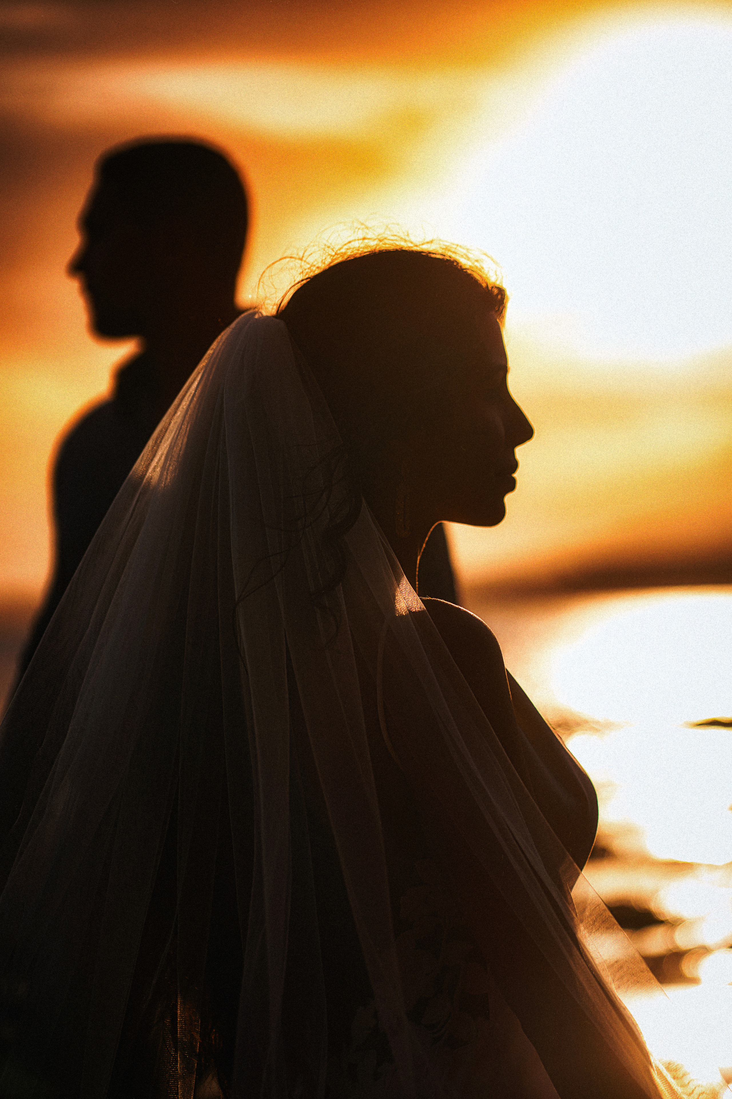 A couple in wedding clothes standing with the sunset background