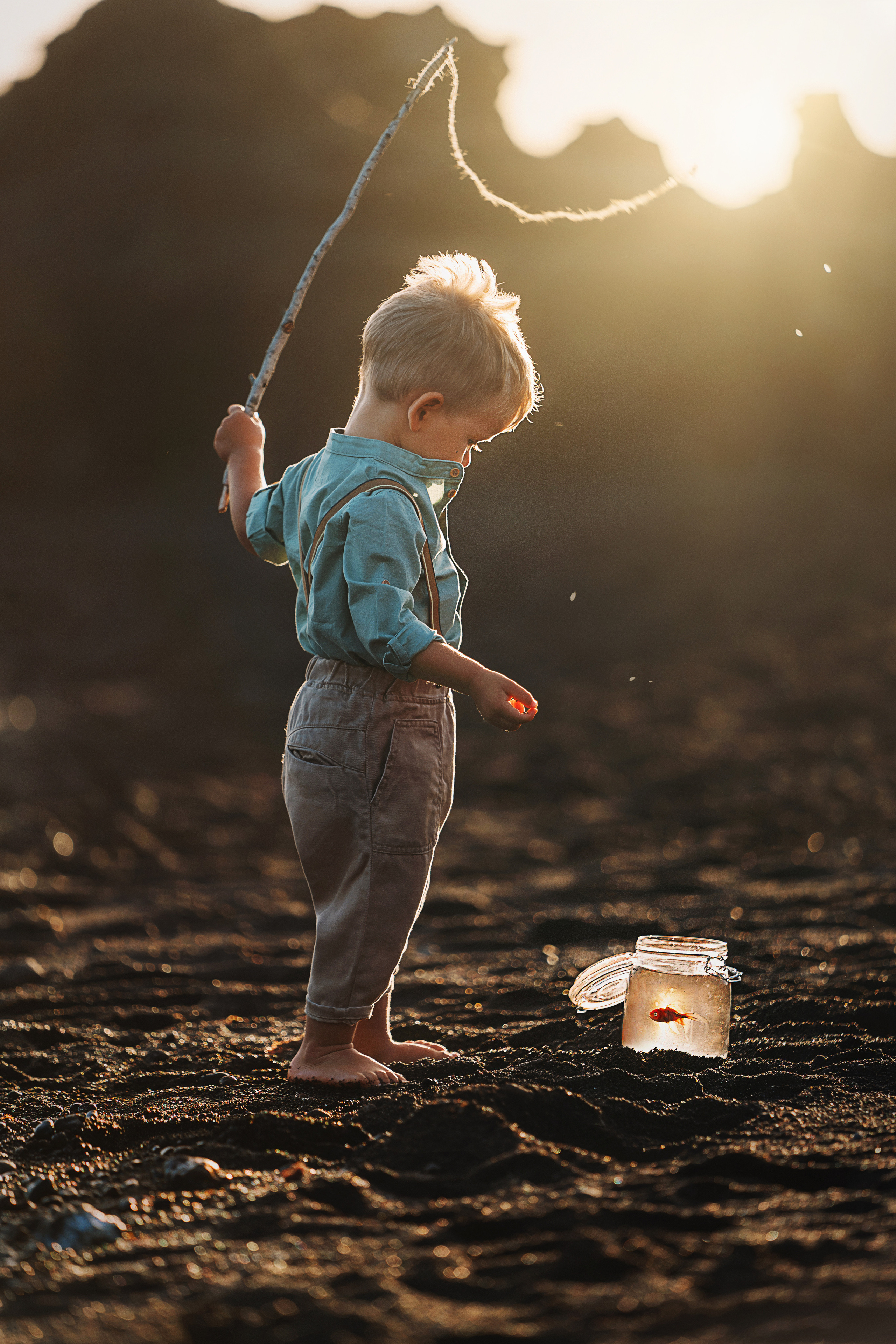 A boy is on the shore fishing with a rod