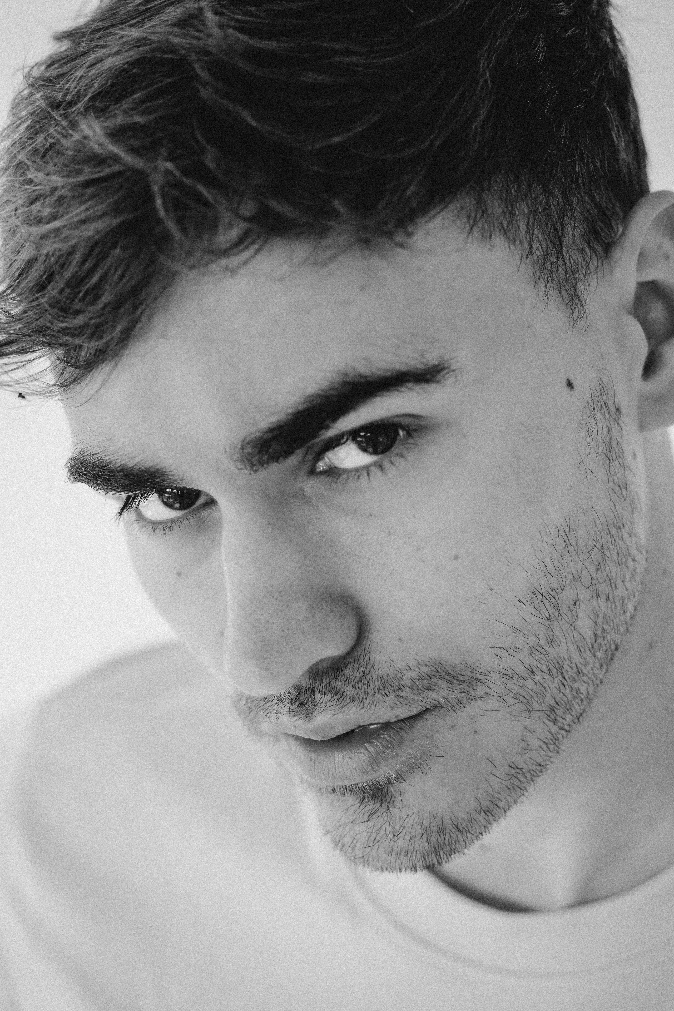 Close-up black and white portrait of a model with intense eye contact. Testshoot. Close-up monochrome portrait of a thoughtful male model with intense eye contact. Confident male model with serious expression and clean styling.