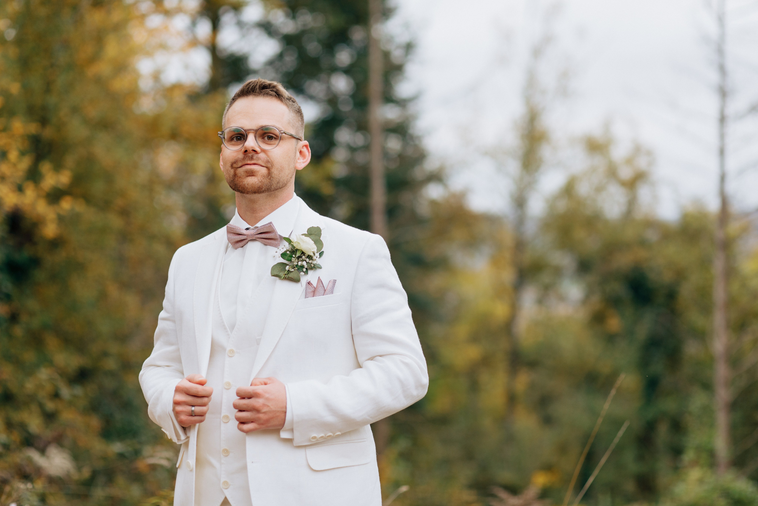 Entspannter und stilvoller Porträt des Bräutigams vor dem Waldhintergrund.