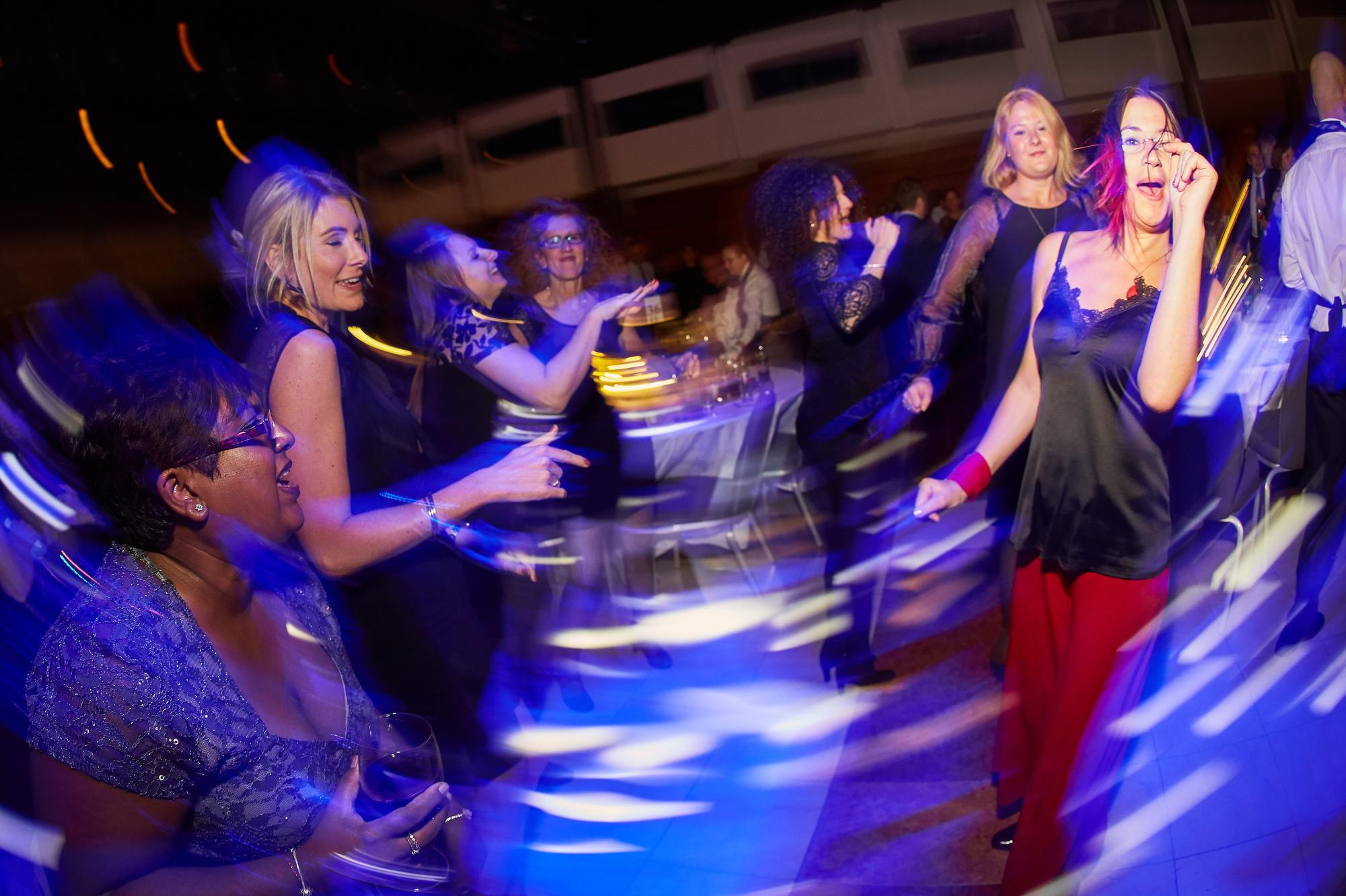 Ladies tear it up on the dance floor under the colorful lights as a band peforms.