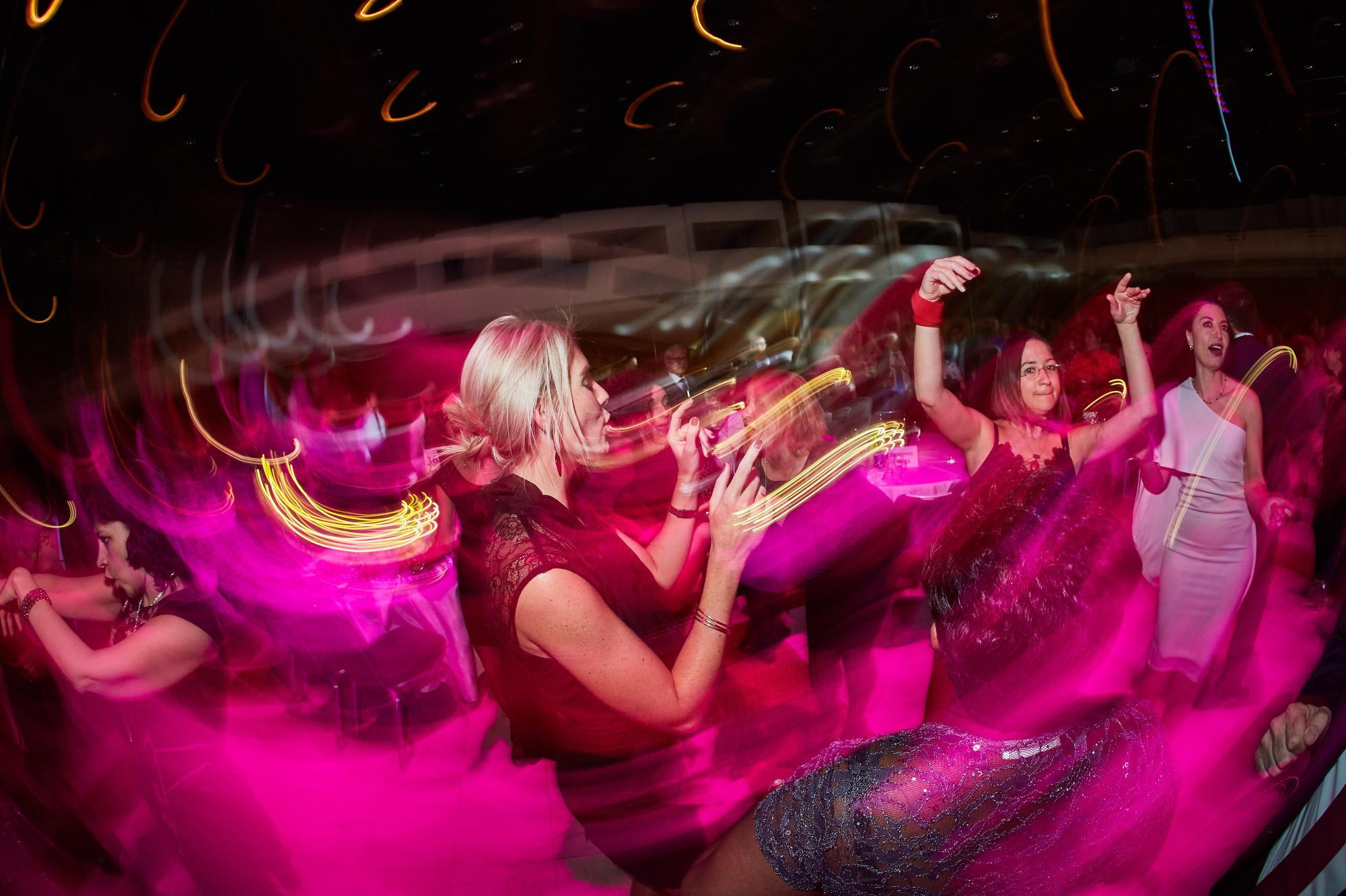 Ladies pump their hands in the air as they dance atop the colorful dance floor.