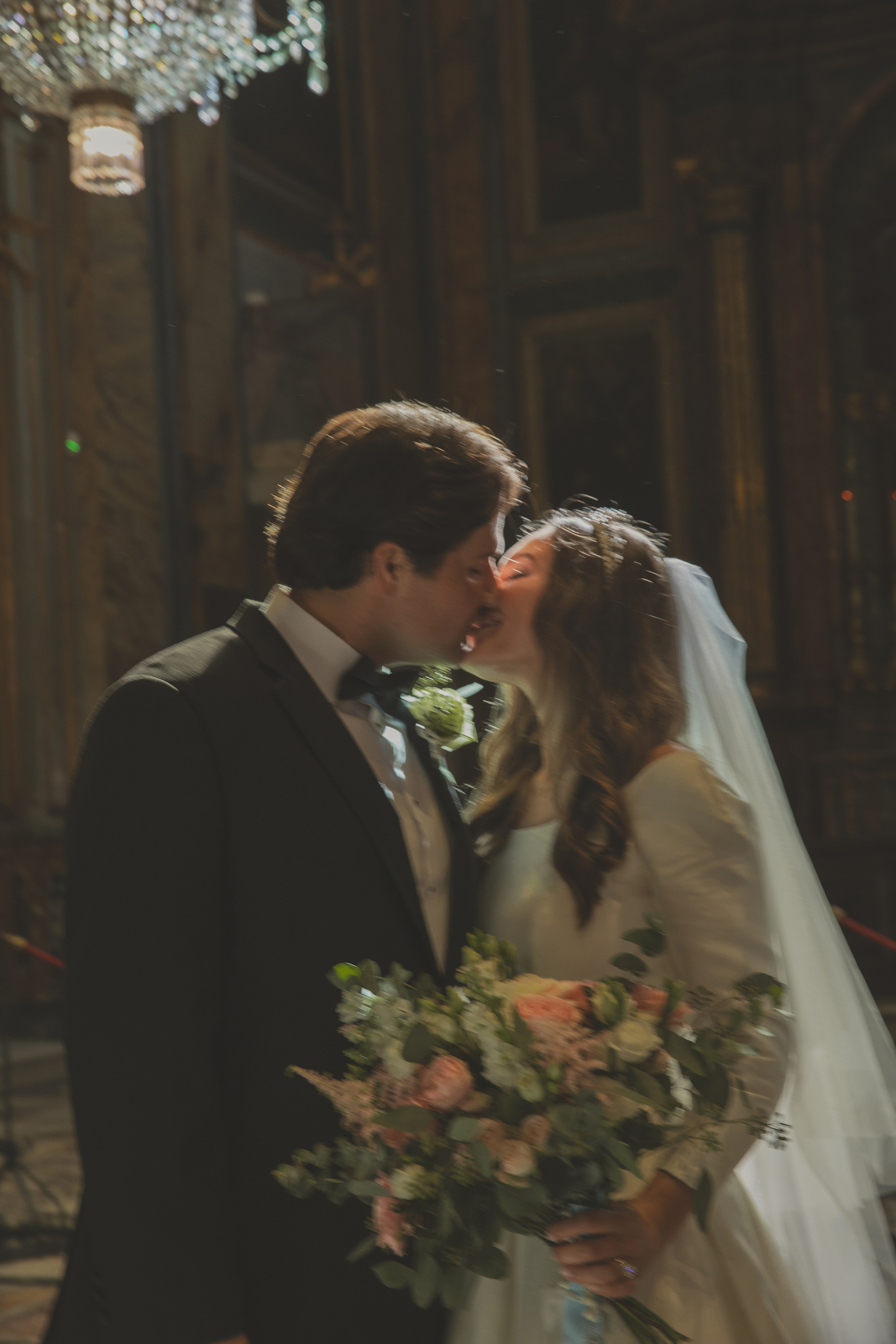 A newly married couple sharing a kiss under the chandeliers at Santa Maria in Aracoeli after their wedding.