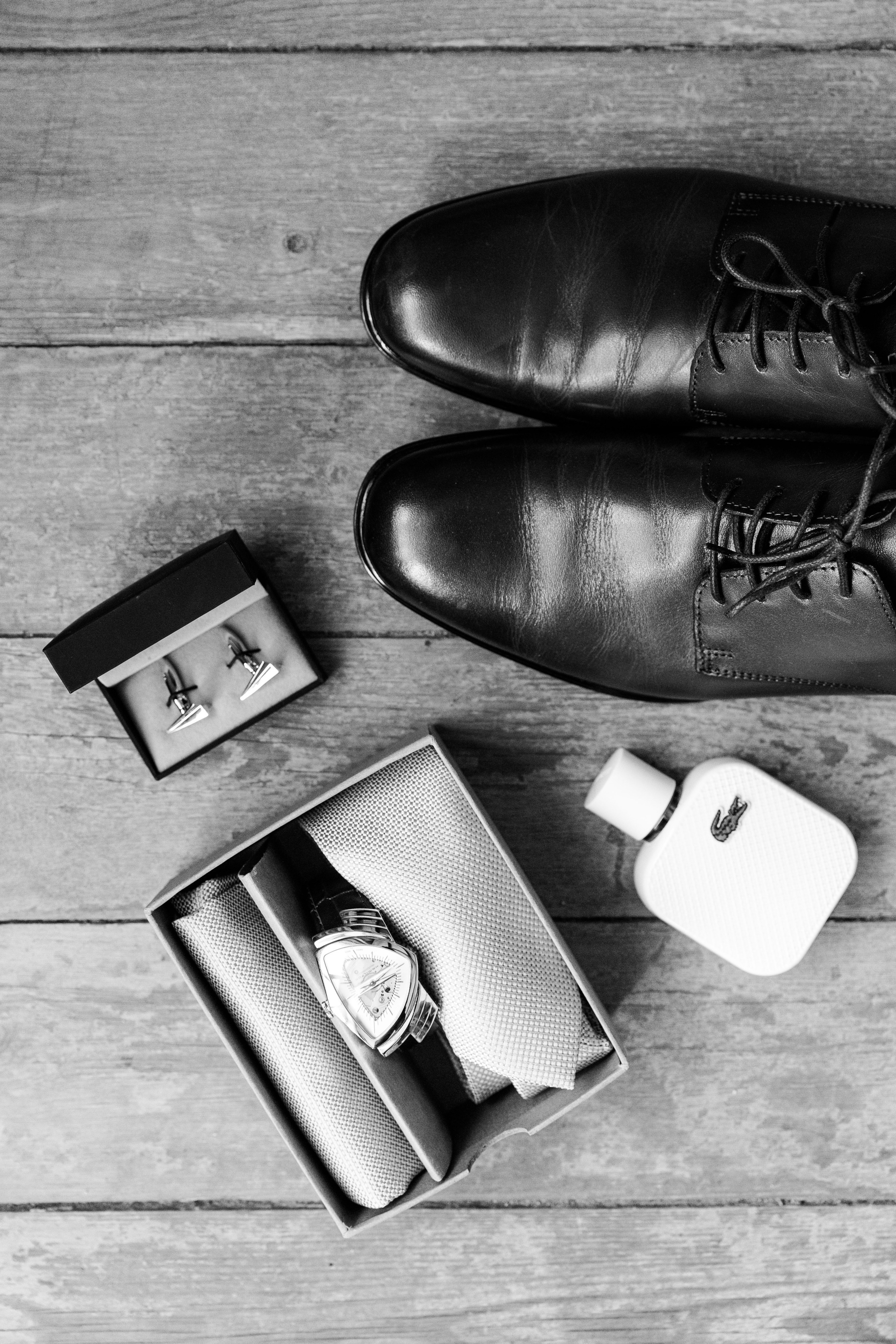 Close-up of the groom's wedding shoes, perfume, cufflinks, and boutonniere, styled for a Barcelona wedding.