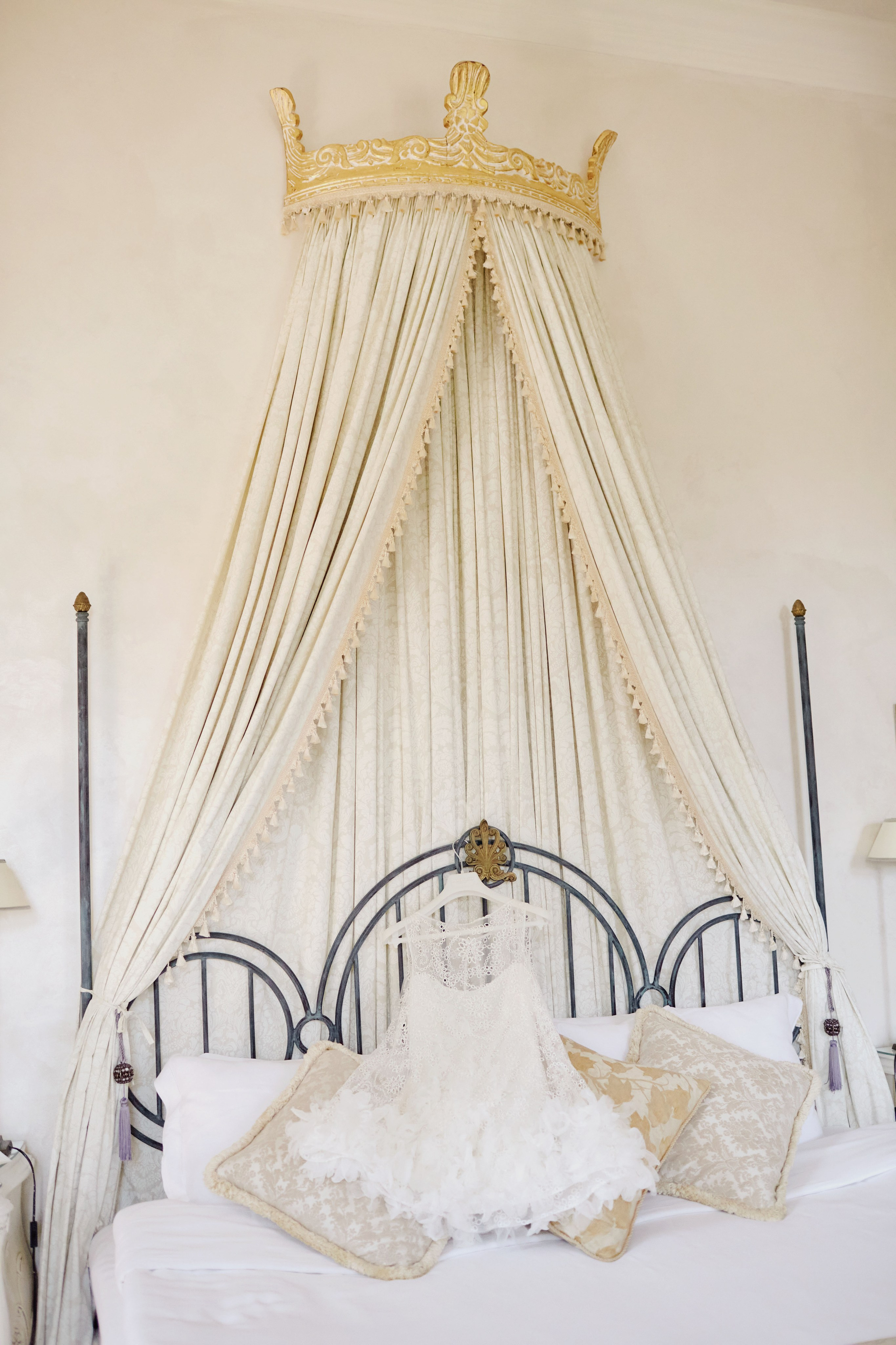 Wedding dress laid on a stylish antique bed in the suite of a historic chateau.