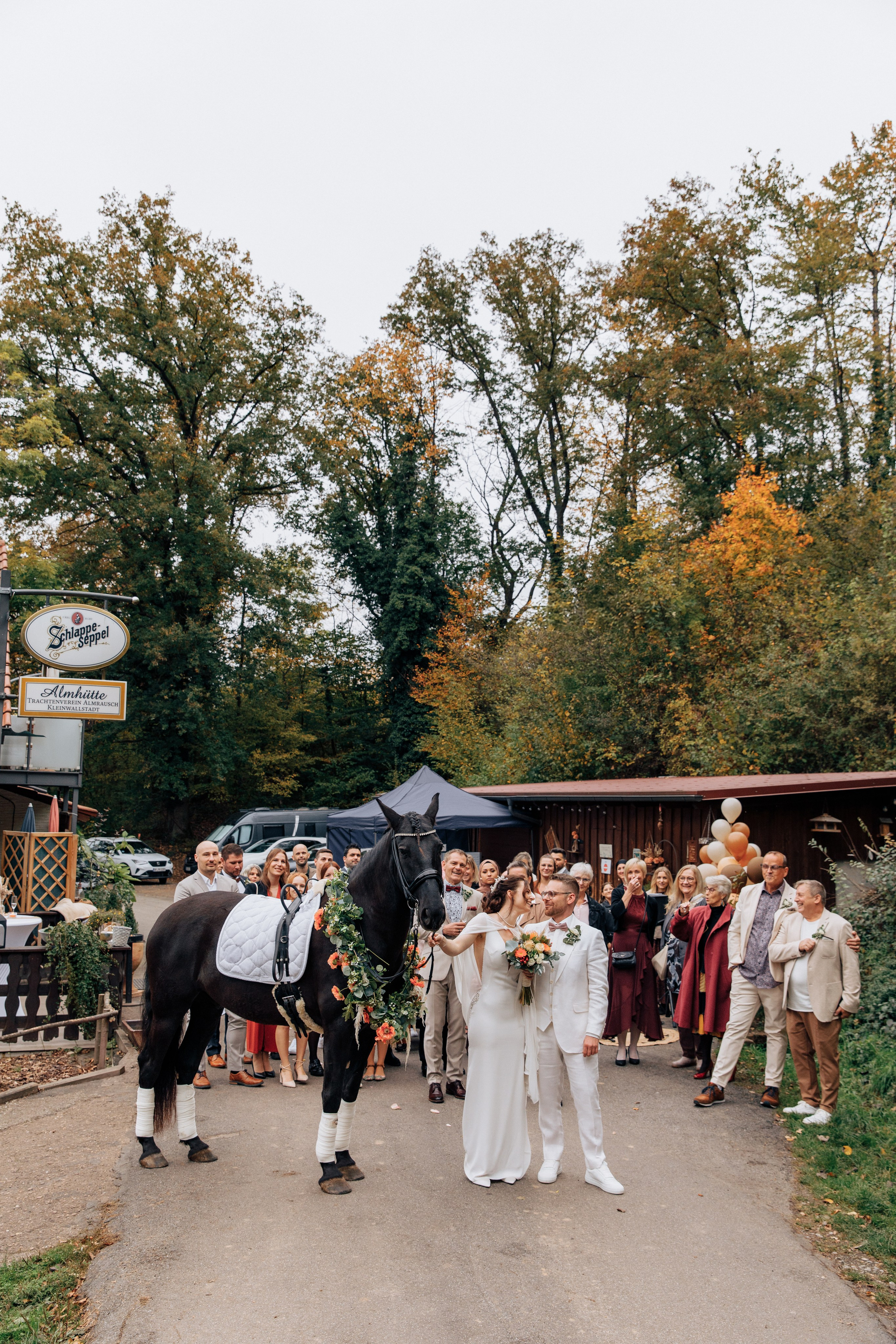 Alle Gäste stehen zusammen mit dem Brautpaar und einem Pferd vor der Hochzeitslocation Almhütte Kleinwallstadt, umgeben von wunderschöner Hochzeitsdekoration. Perfekte Hochzeitsfotos für den besonderen Tag.