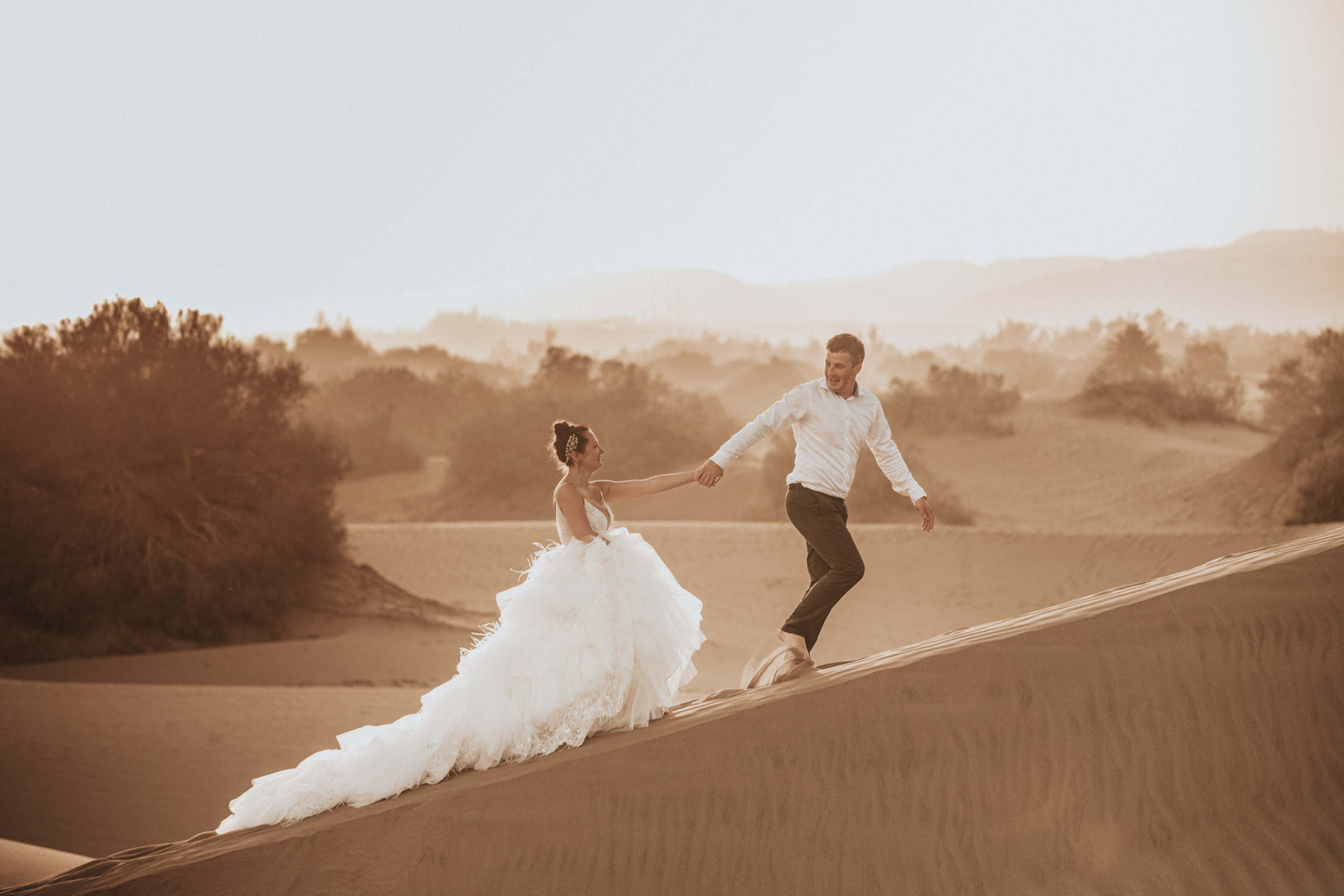 A bride and groom standing on top of a sand en Dunas Maspalomas Photo shoot