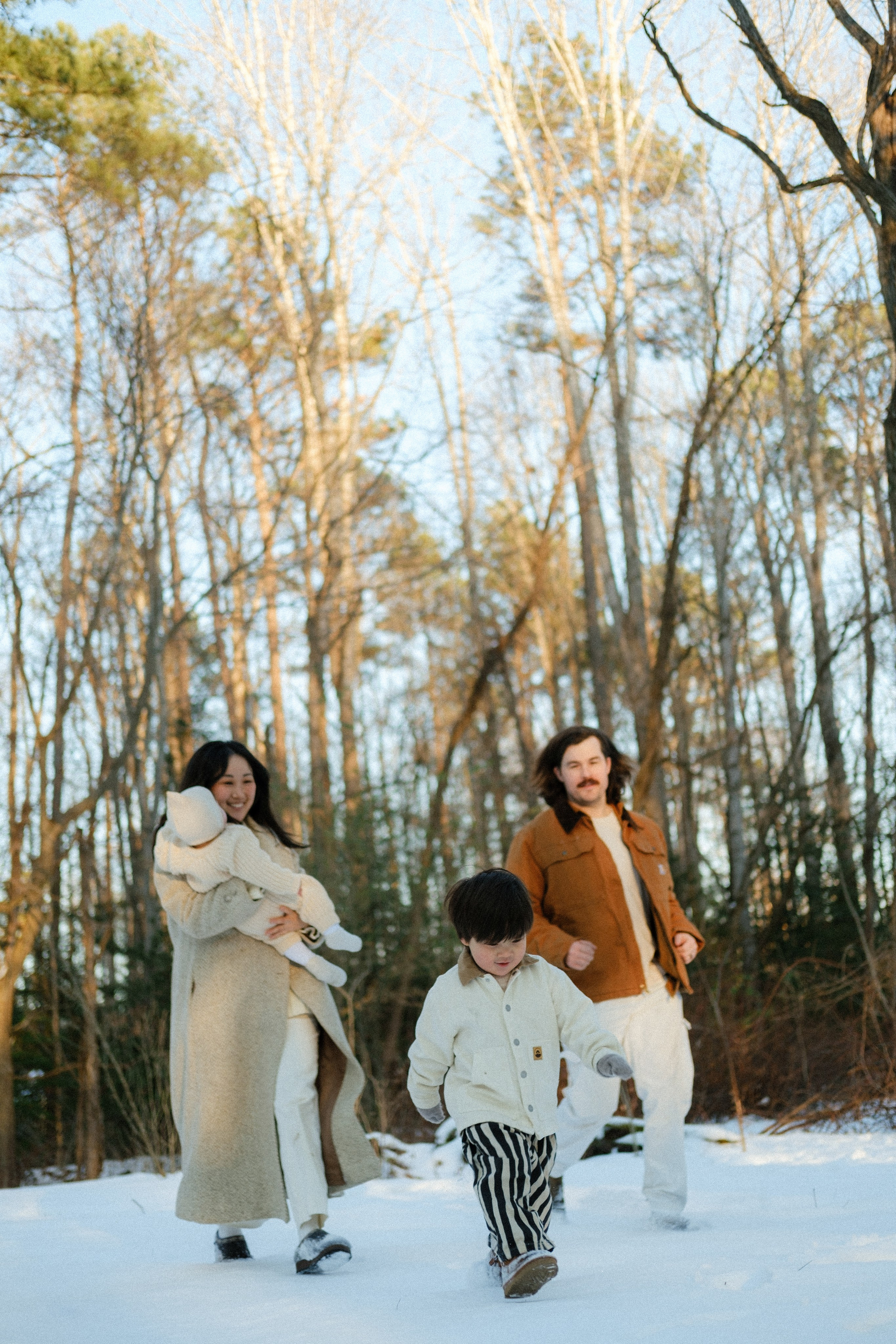Family running through a snowy forest trail near Richmond, VA — a winter wonderland photo session.