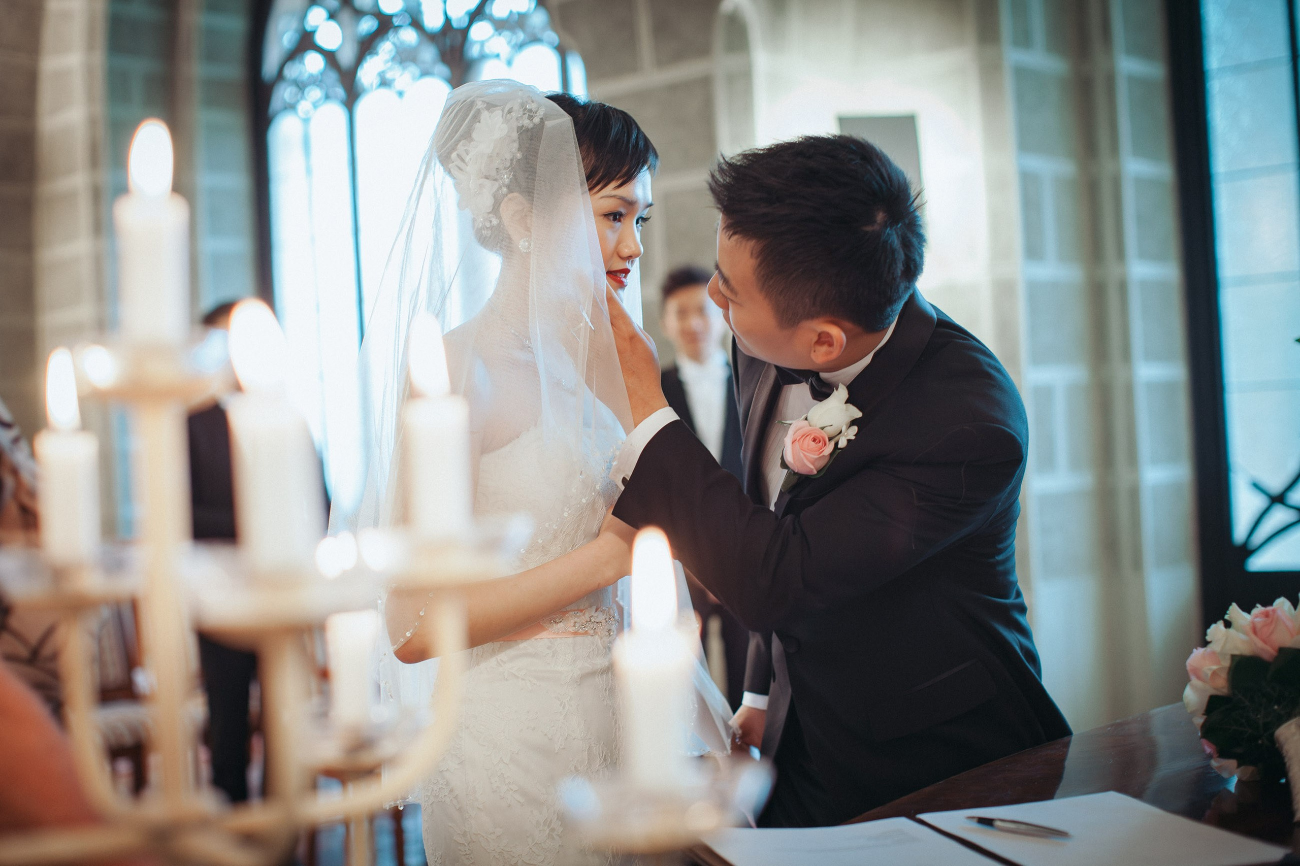 The groom from Hong Kong lovingly wipes his brides face during their romantic candlelit castle wedding at the State Chateau of Hluboka.