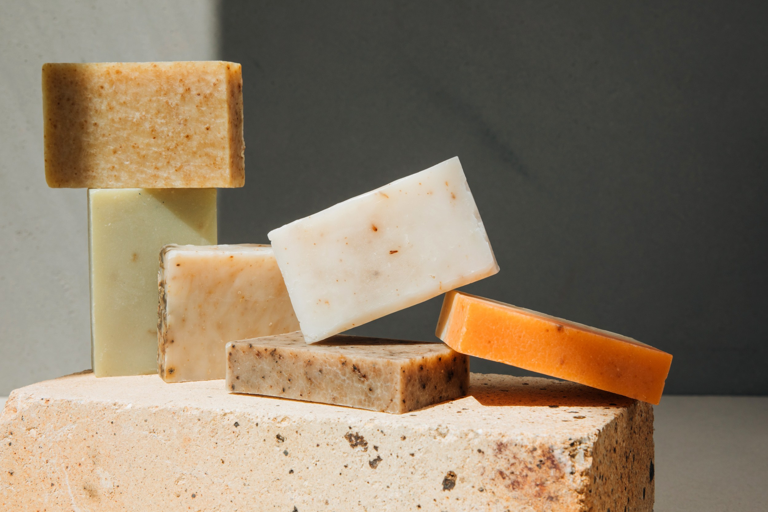 Collection of organic soap bars with visible natural textures, balanced artistically on a stone