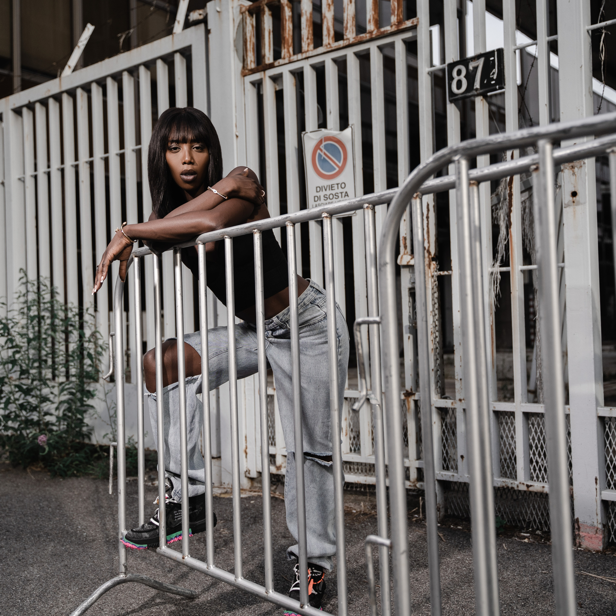 Woman in casual attire leaning on metal barricade on an urban street