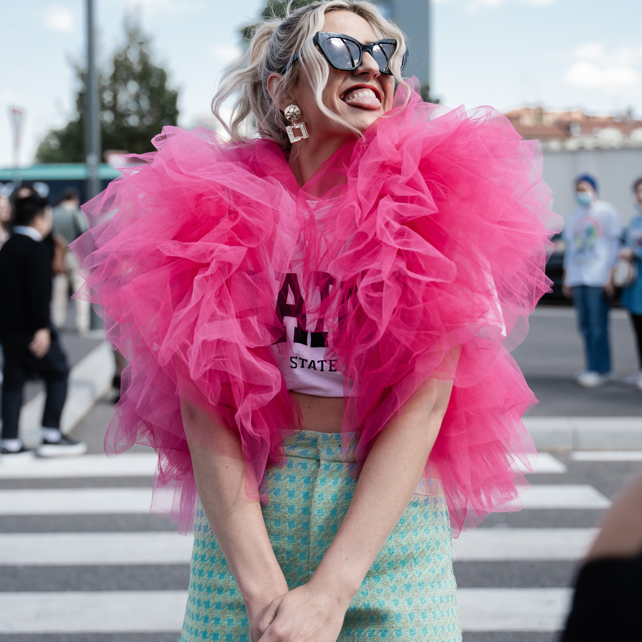 Cheerful woman in a pink ruffled top and pastel shorts, striking a playful pose during Milan Fashion Week