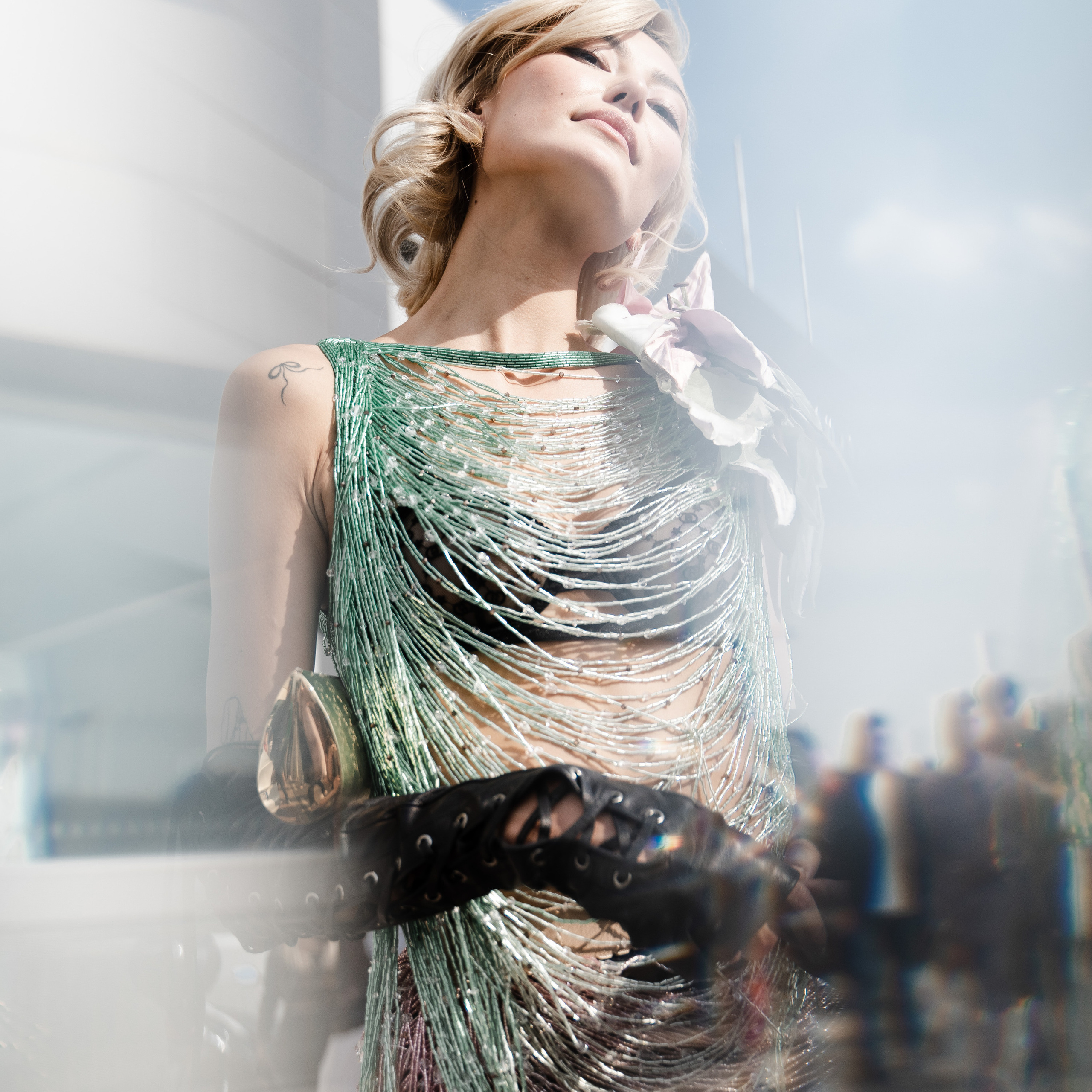 Milan Fashion Week fashion editorial – a model in a shimmering green fringe dress under natural light