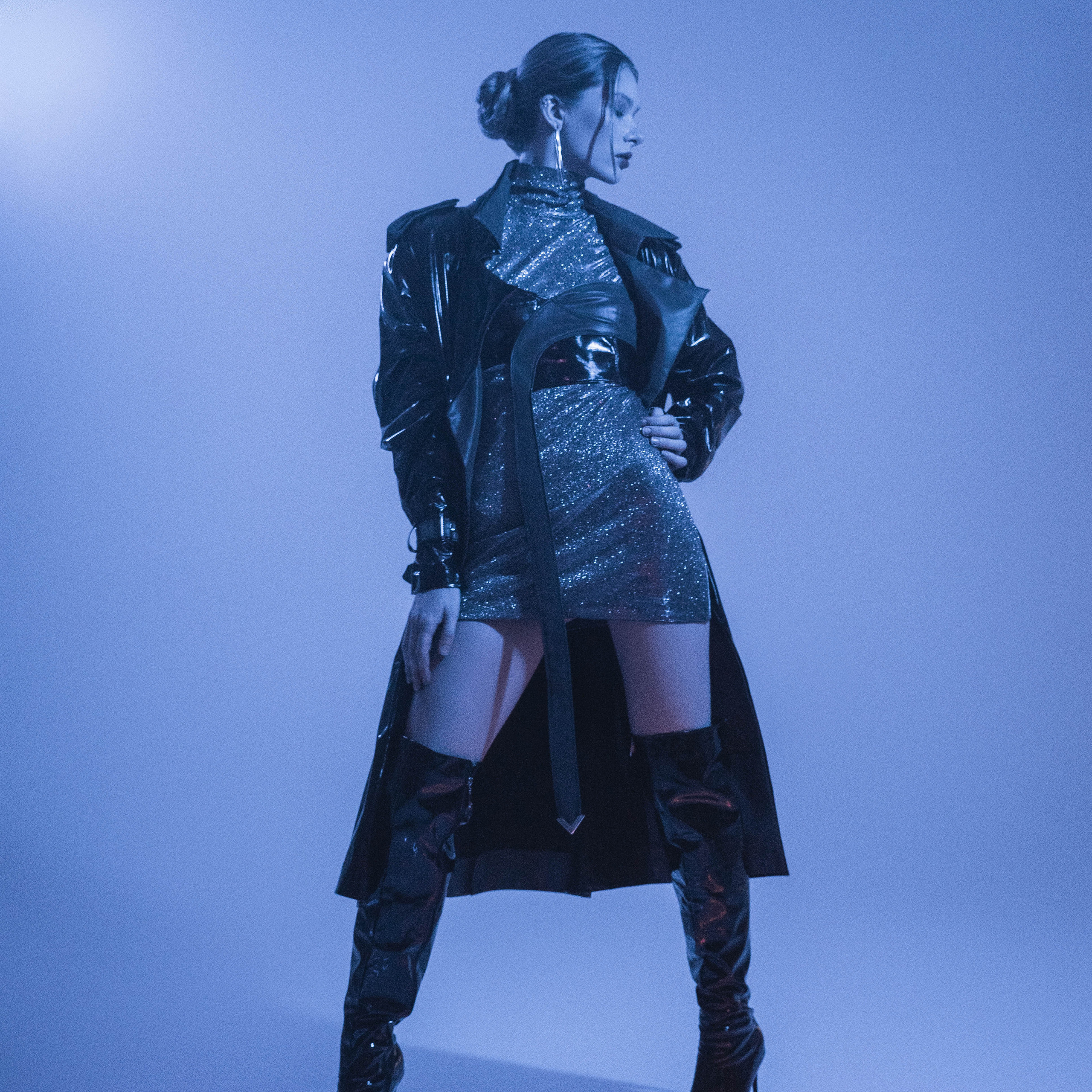Fashionable model in a futuristic black and silver outfit posing under blue lighting