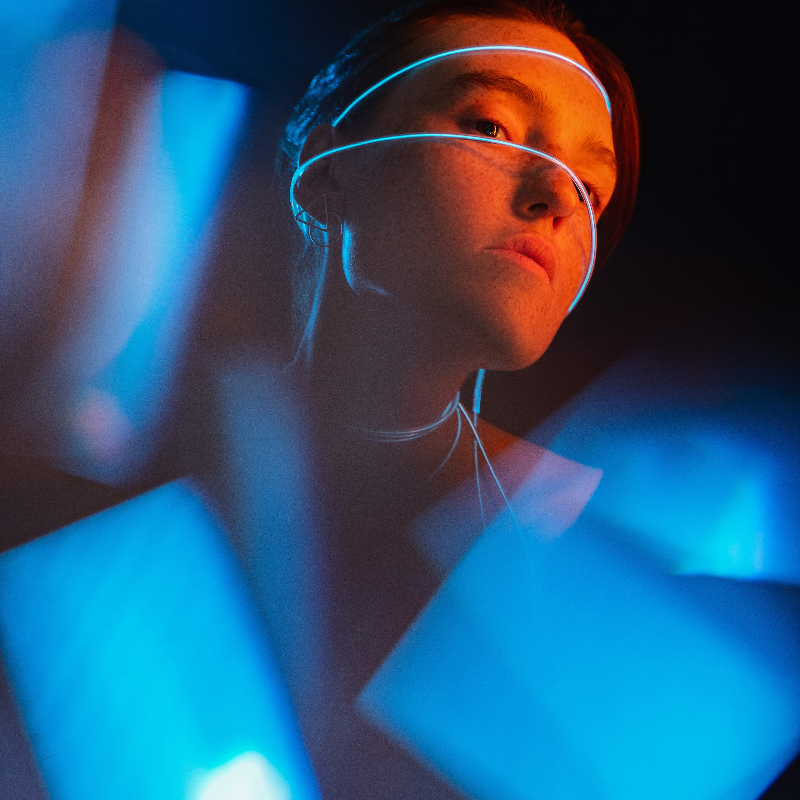 Portrait of a woman with glowing strips of light reflecting on her face amidst darkness