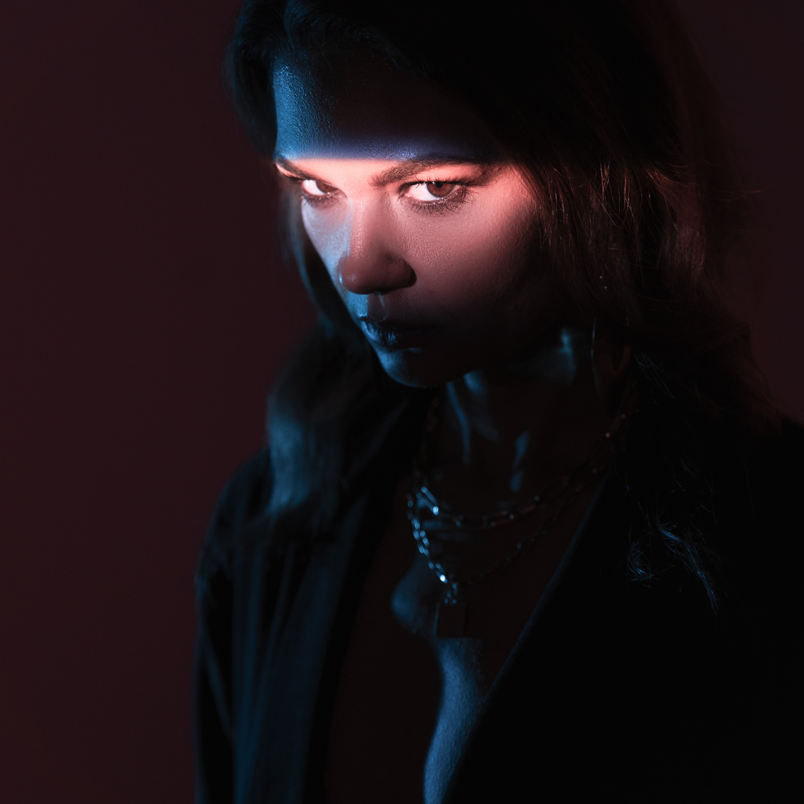 Woman with striking blue light on her face against a dark background
