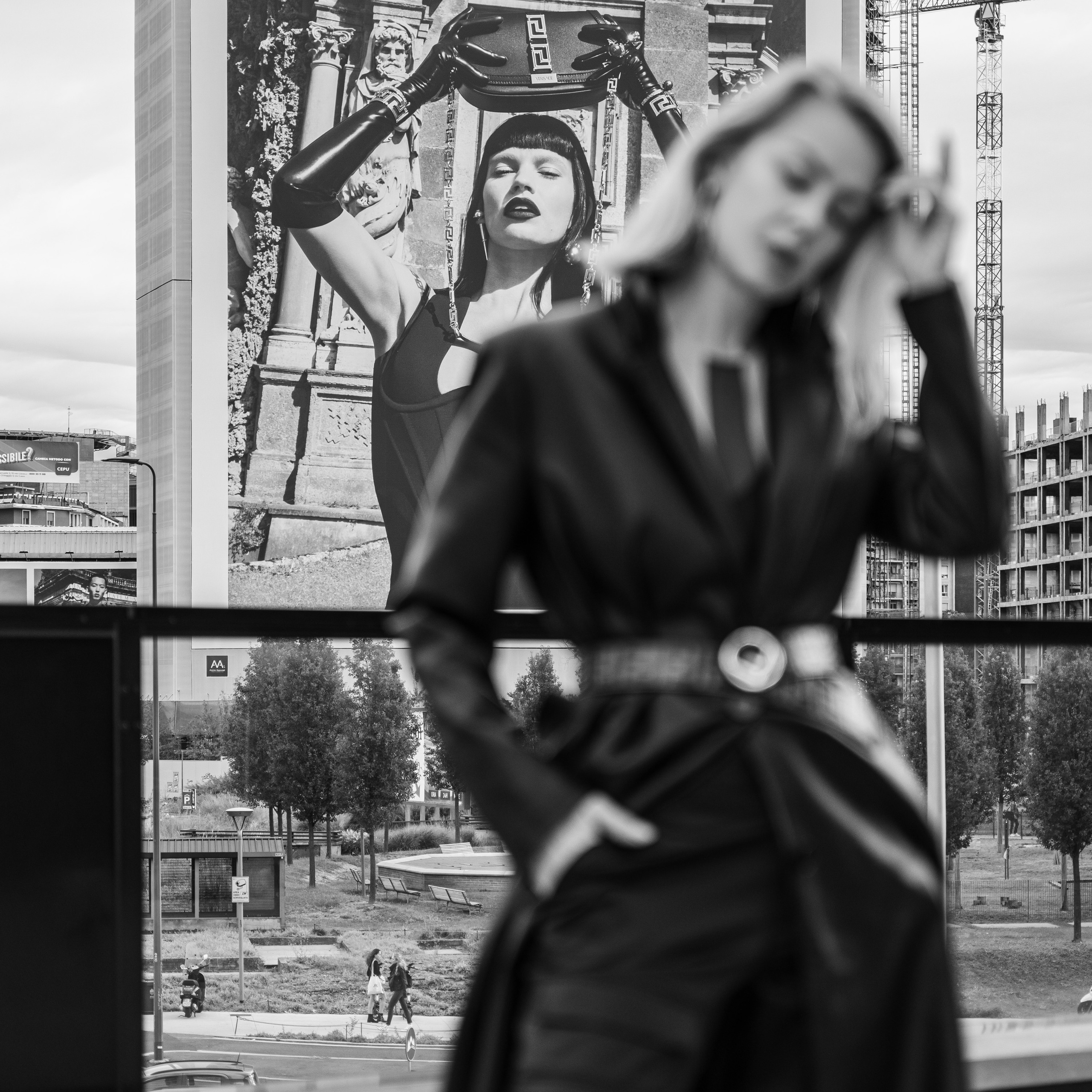 Woman in black attire with blurred motion against a billboard background featuring Versace advertisement