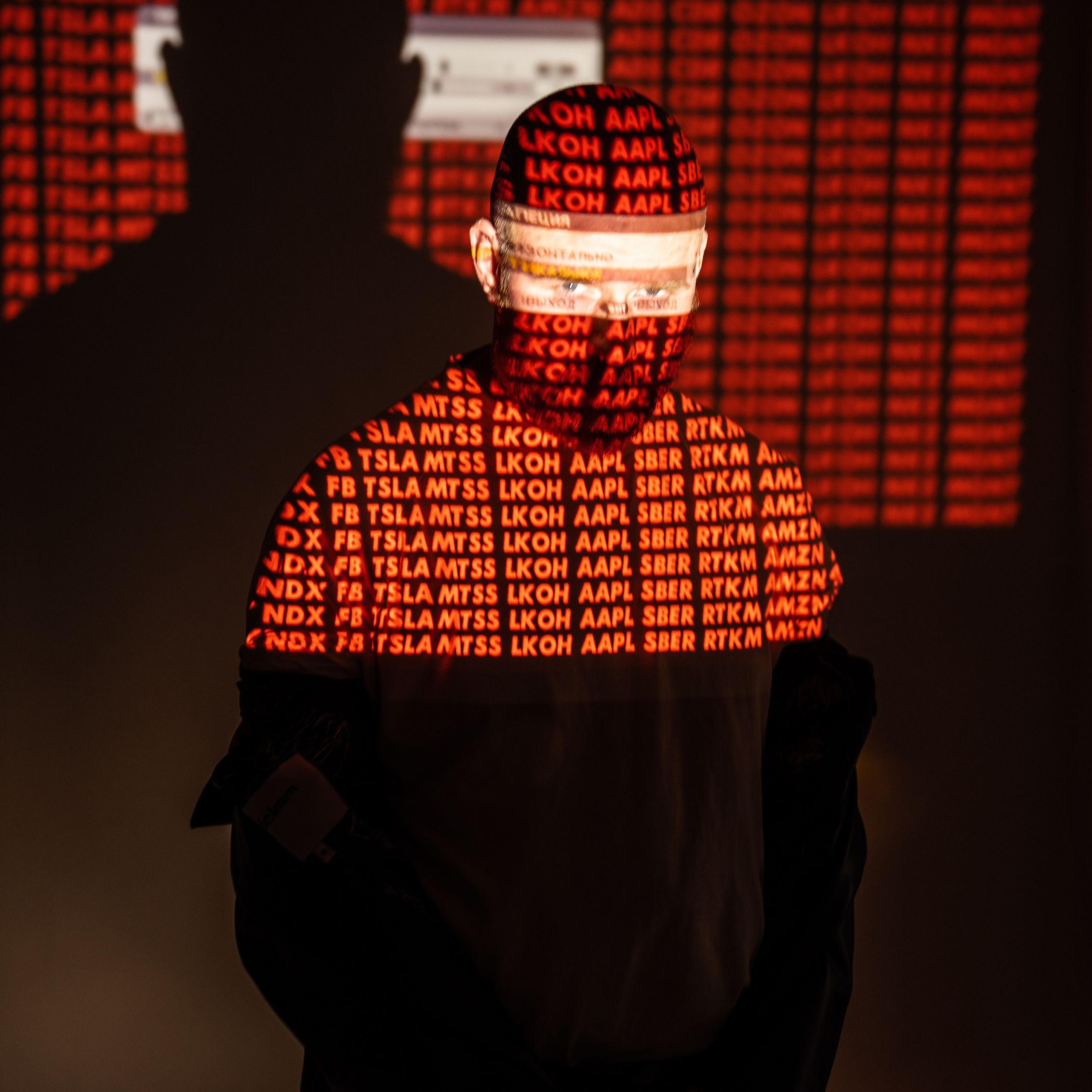 Silhouette of a man with stock market tickers projected on his face and torso