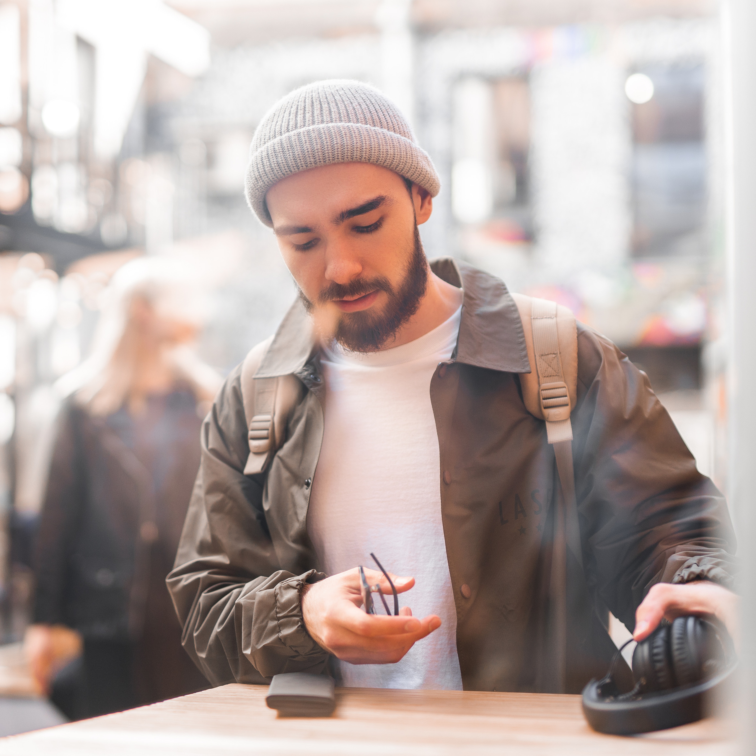 Hipster man with beard and glasses using smartphone in urban setting