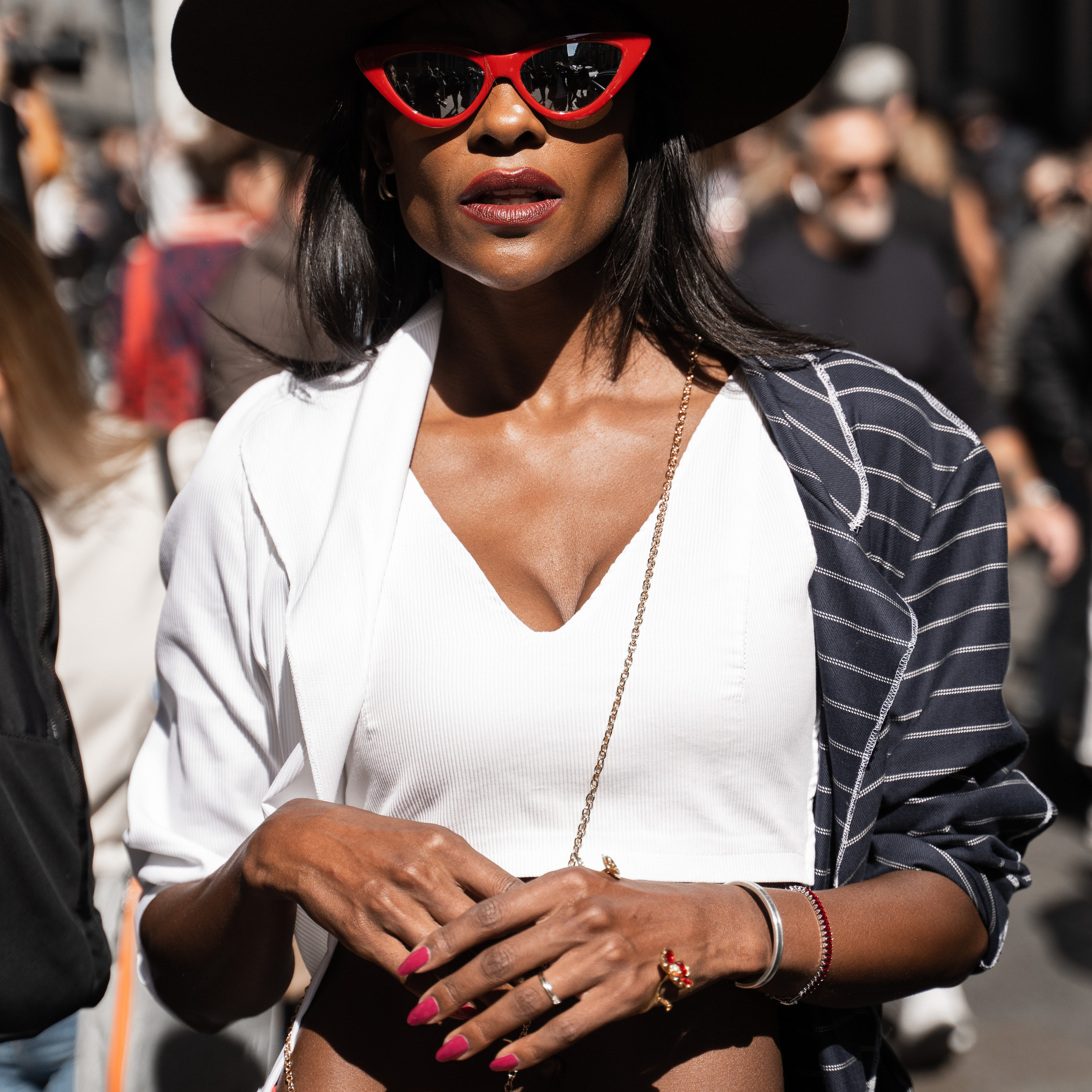 Elegant woman in a wide-brimmed hat and red sunglasses seen at Milan Fashion Week