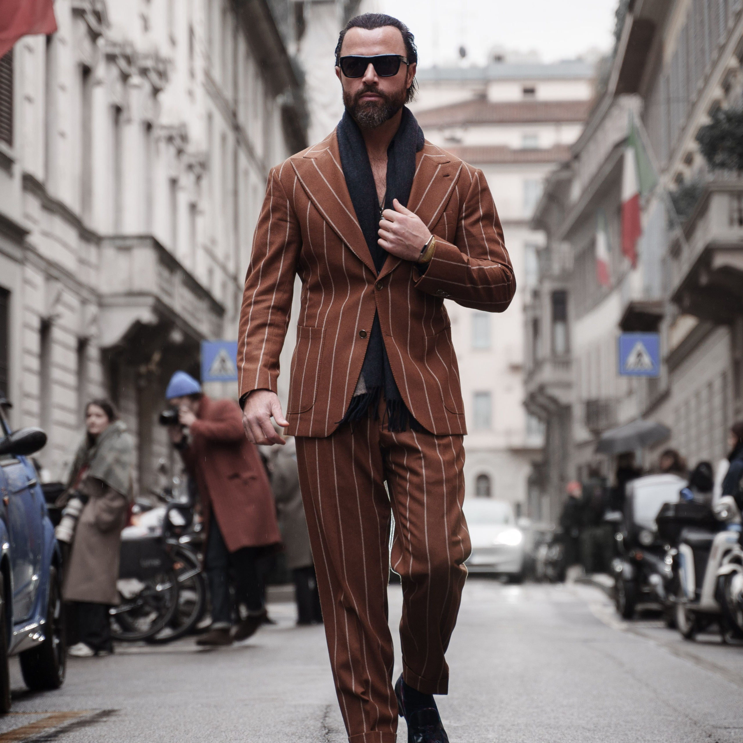 Street style photography in Milan – a man in a brown striped suit walking confidently during Milan Fashion Week