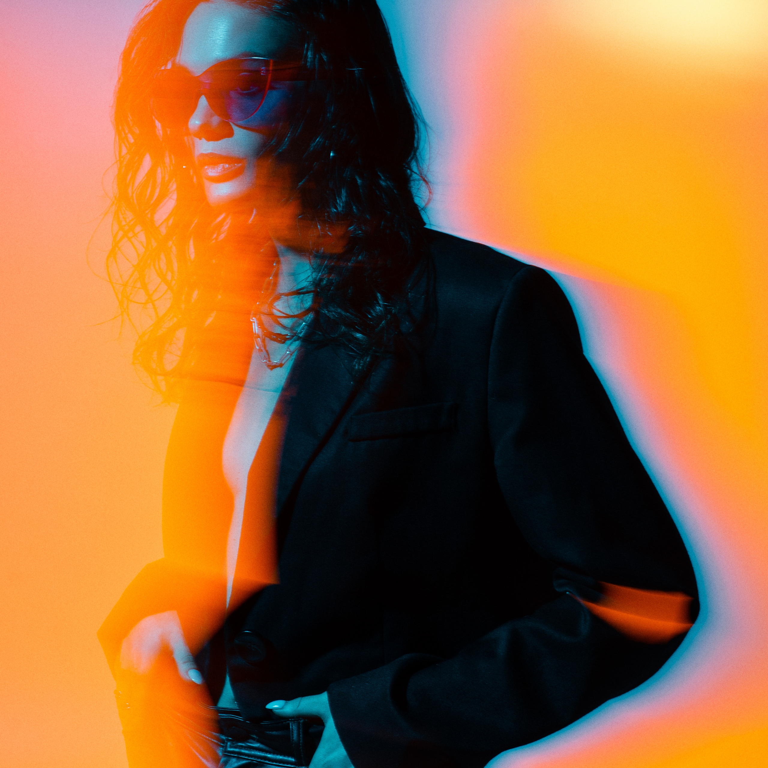 Woman with wavy hair wearing sunglasses with vibrant red and blue neon light effects