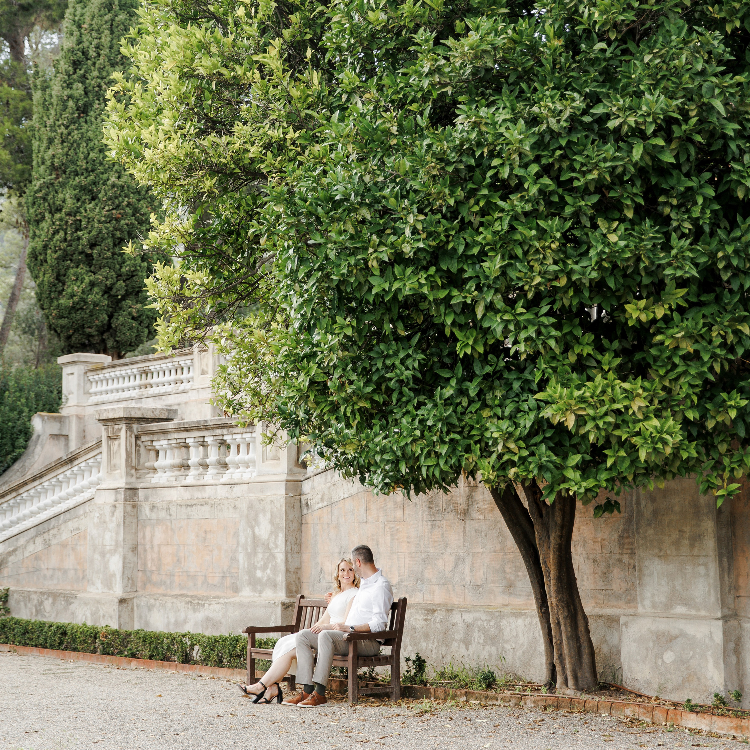 Engaged couple sitting under a green tree and embracing the moment