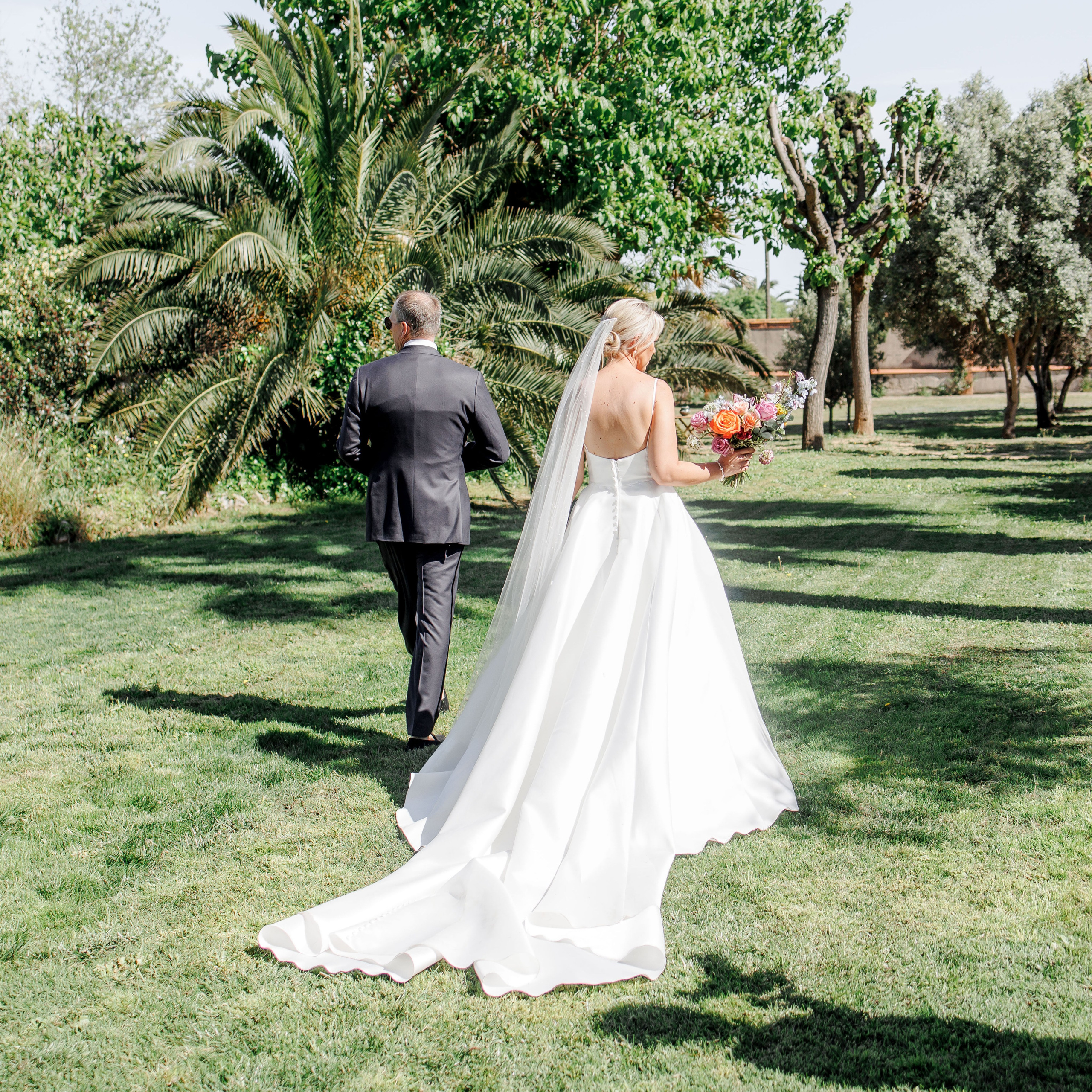 The bride and groom are walking in a lush garden during their wedding in Barcelona