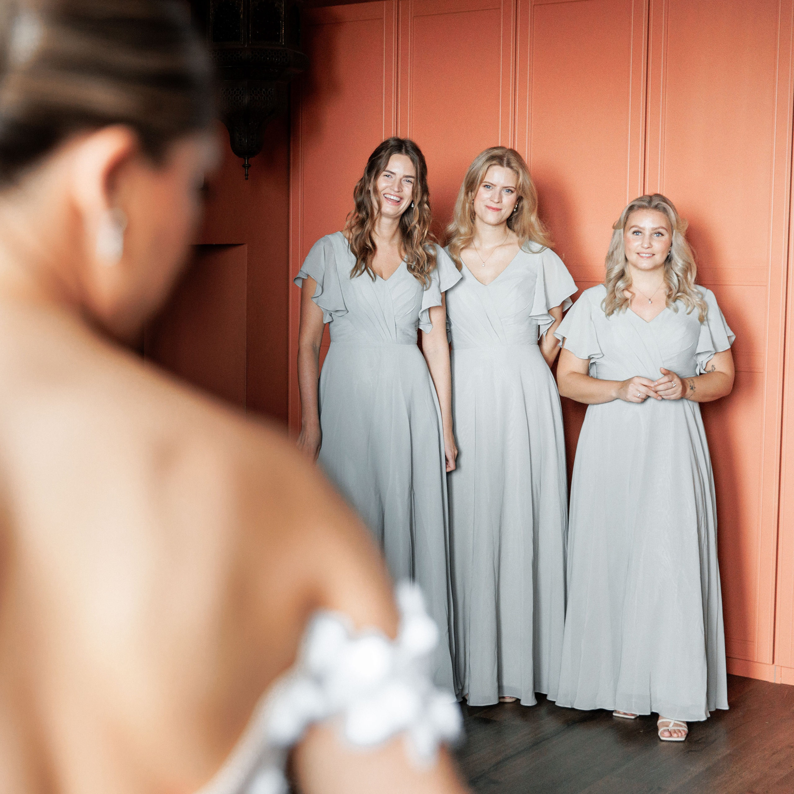 Bridesmaids in matching dresses, seeing the bride for the first time