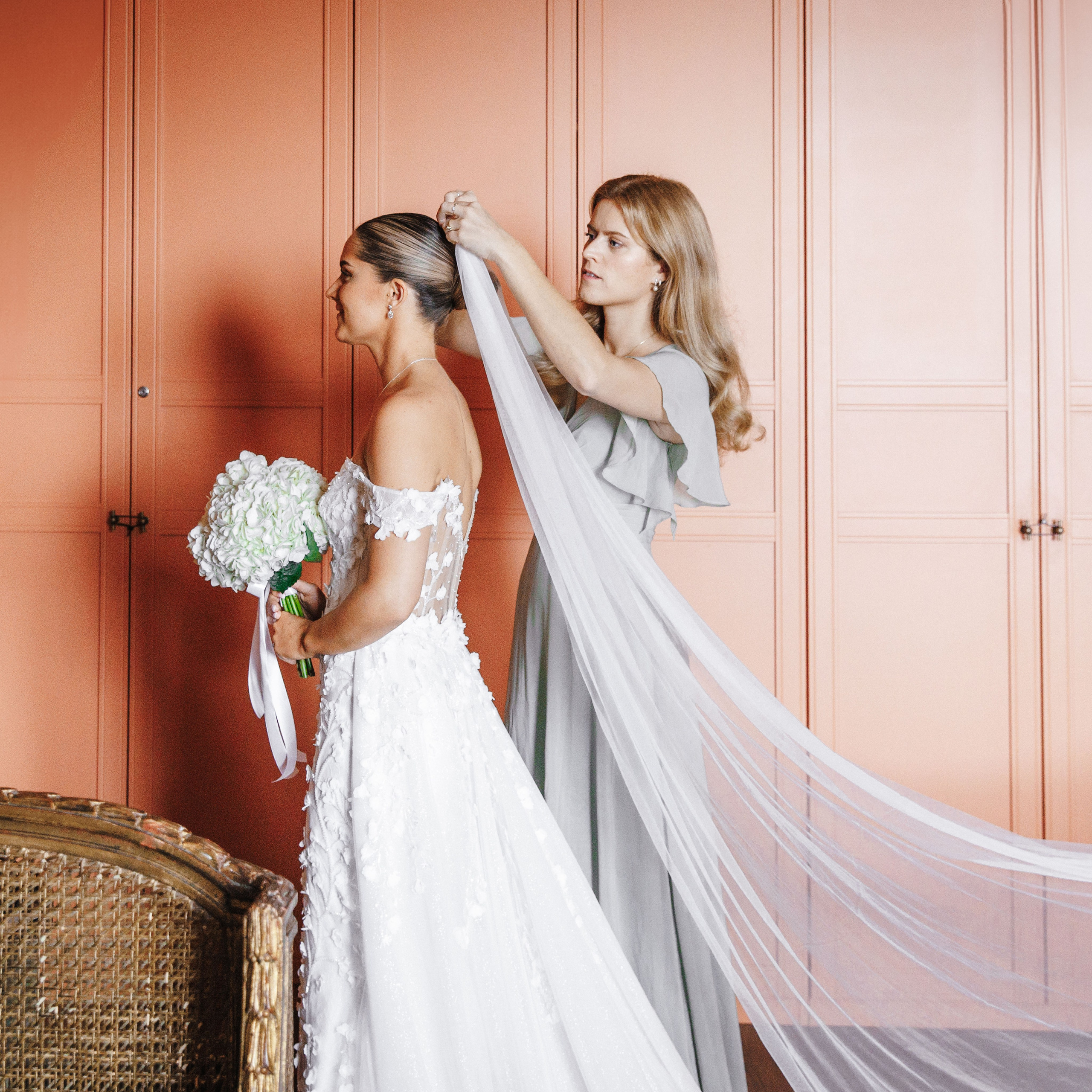 The bridesmaid adjusts the bride's veil before the ceremony starts.