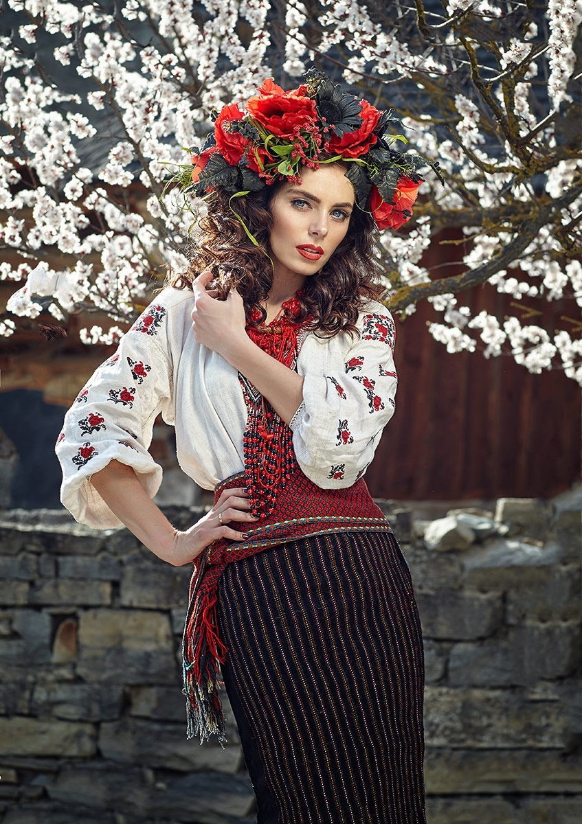 Séance photo de style ukrainien – femme en tenue folklorique avec une couronne florale devant un arbre en fleurs