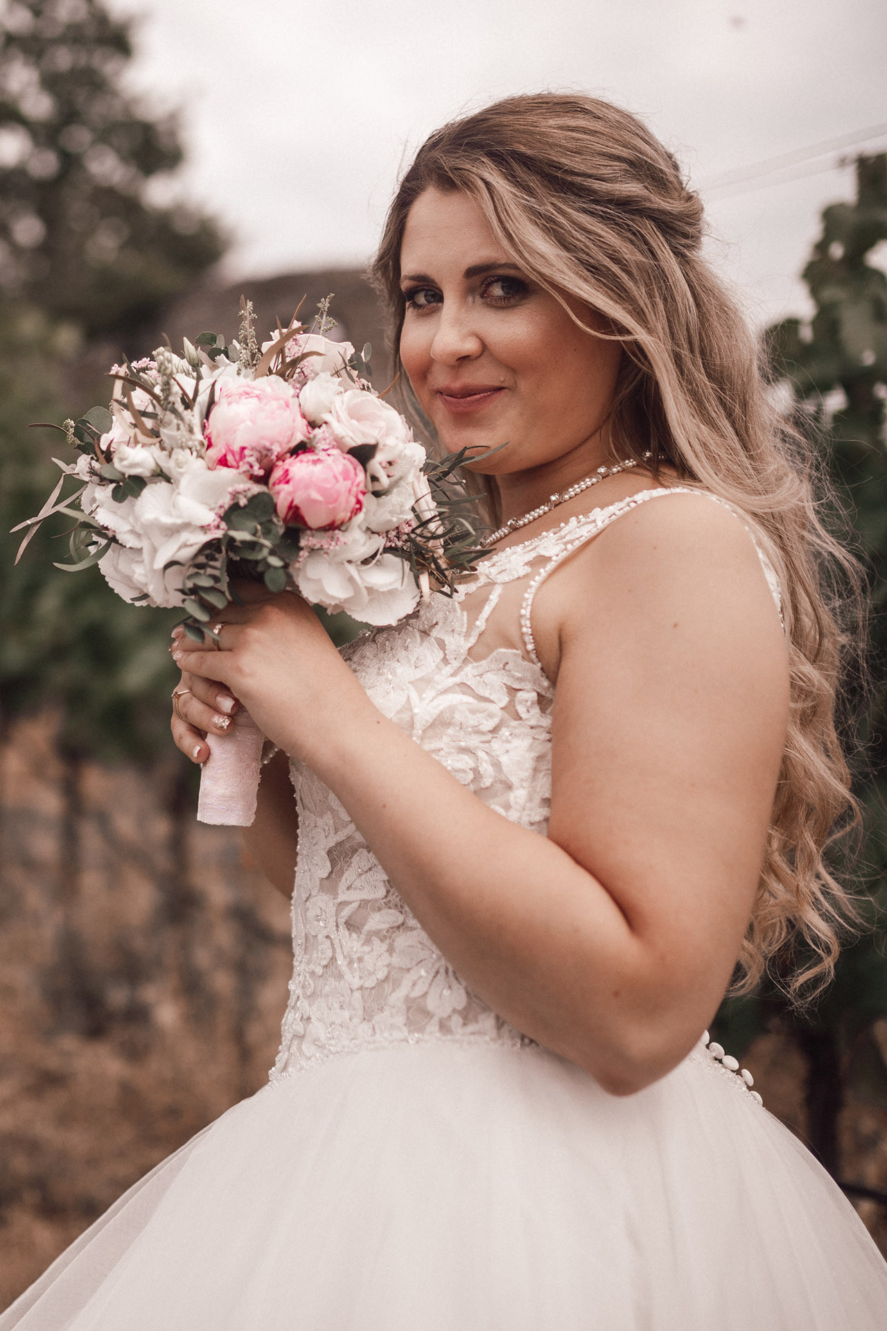 Natürliche Hochzeitsaufnahme – Braut mit Blumenstrauß in der Hand und glücklichem Lächeln