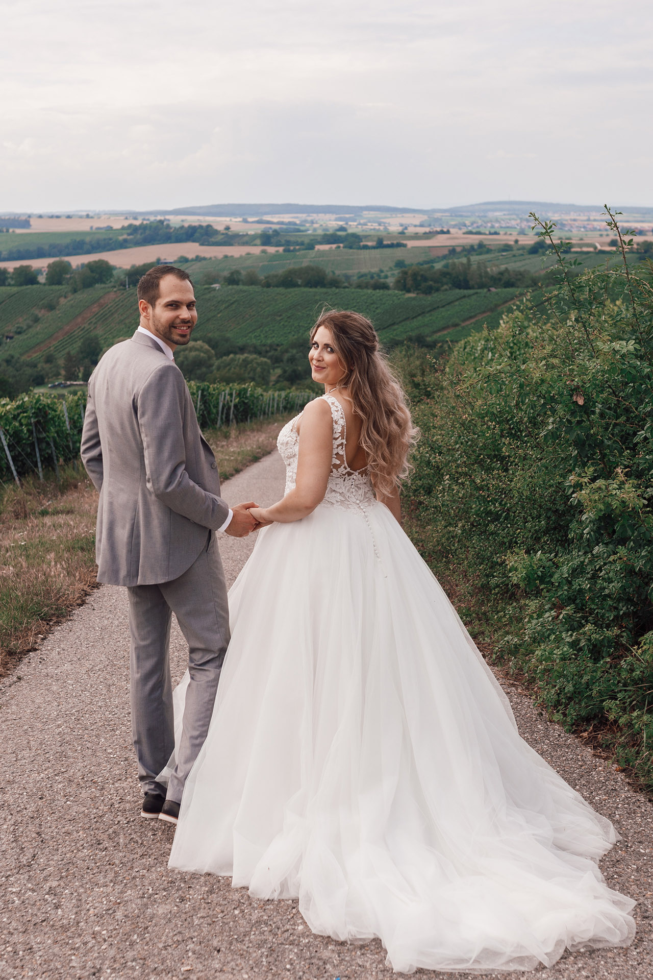 Hochzeitsfoto mit Panorama-Ausblick – Brautpaar hält sich an den Händen