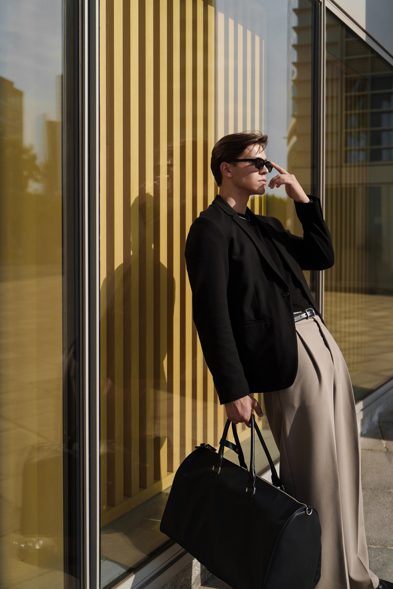 Male fashion model posing near modern architecture with bold shadows in Milan