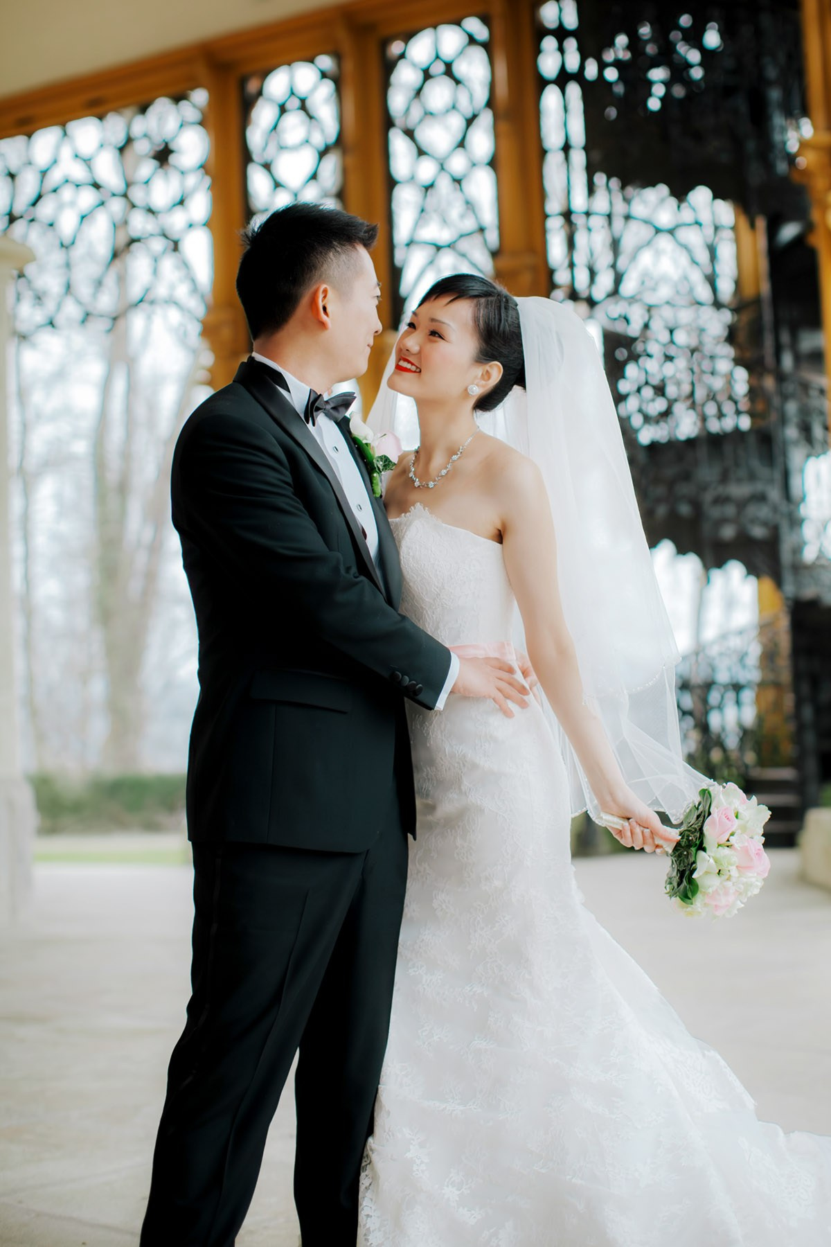 A radiant Hong Kong bride snuggles with her tuxedo wearing groom on the historic grounds of Castle Hluboka during their destination wedding in Czechia.
