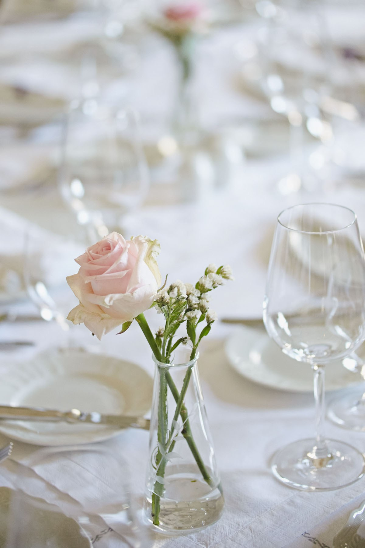 Single rose on an elegantly set dining table in the historic chateau's dining room.