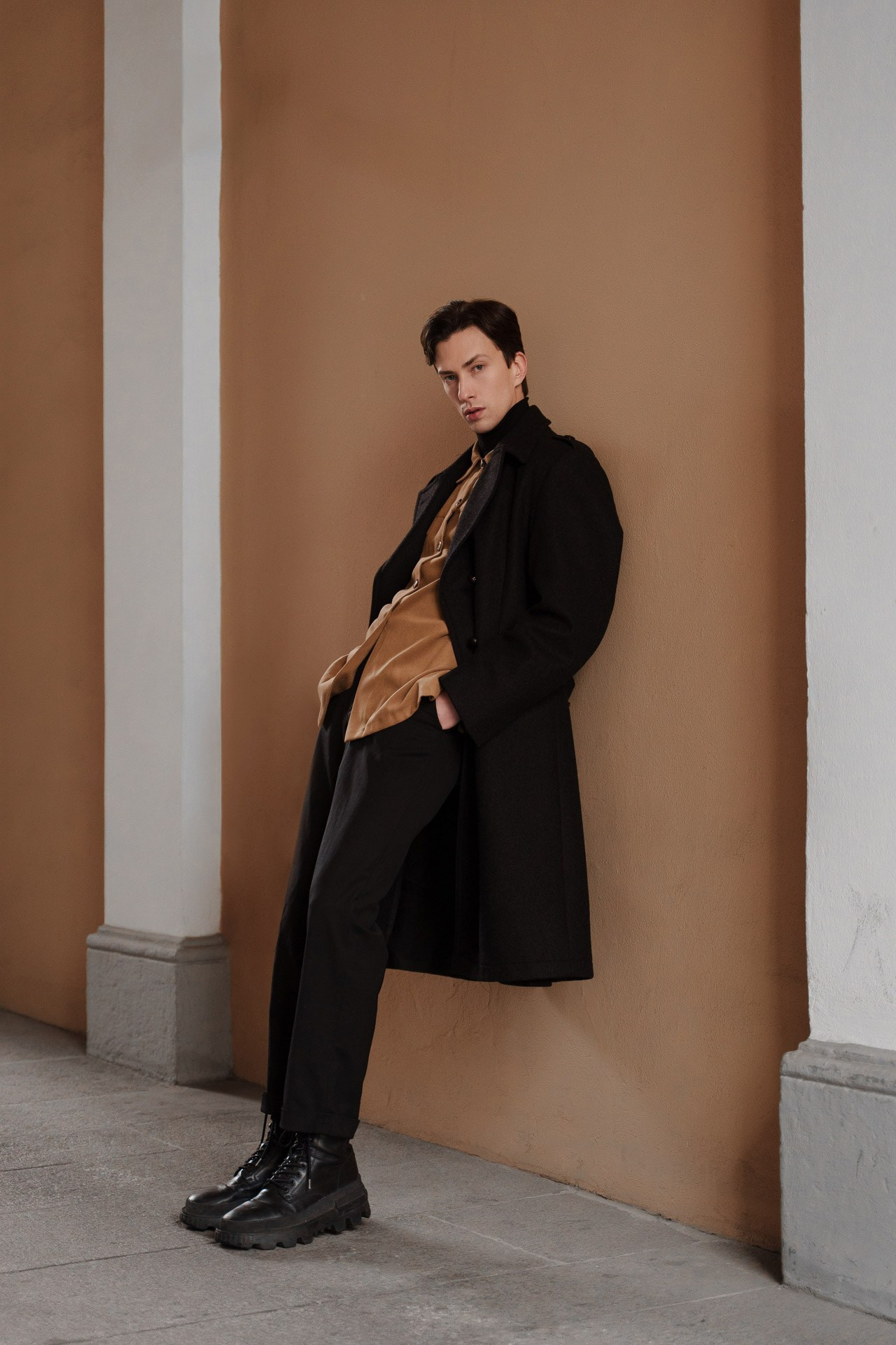 Full-body male model leaning against wall during test shoot in Milan