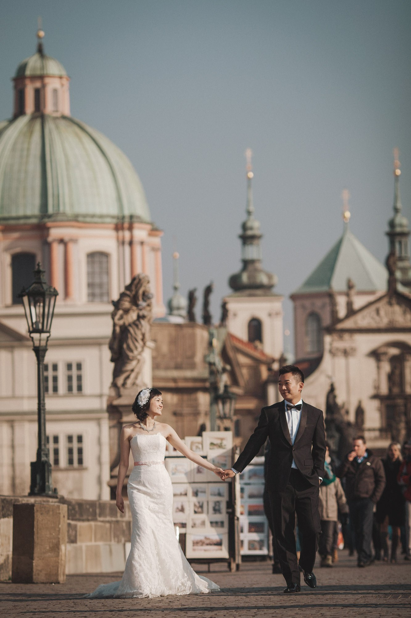 A bride & groom walk across the Charles Bridge in Prague during their love story adventures.