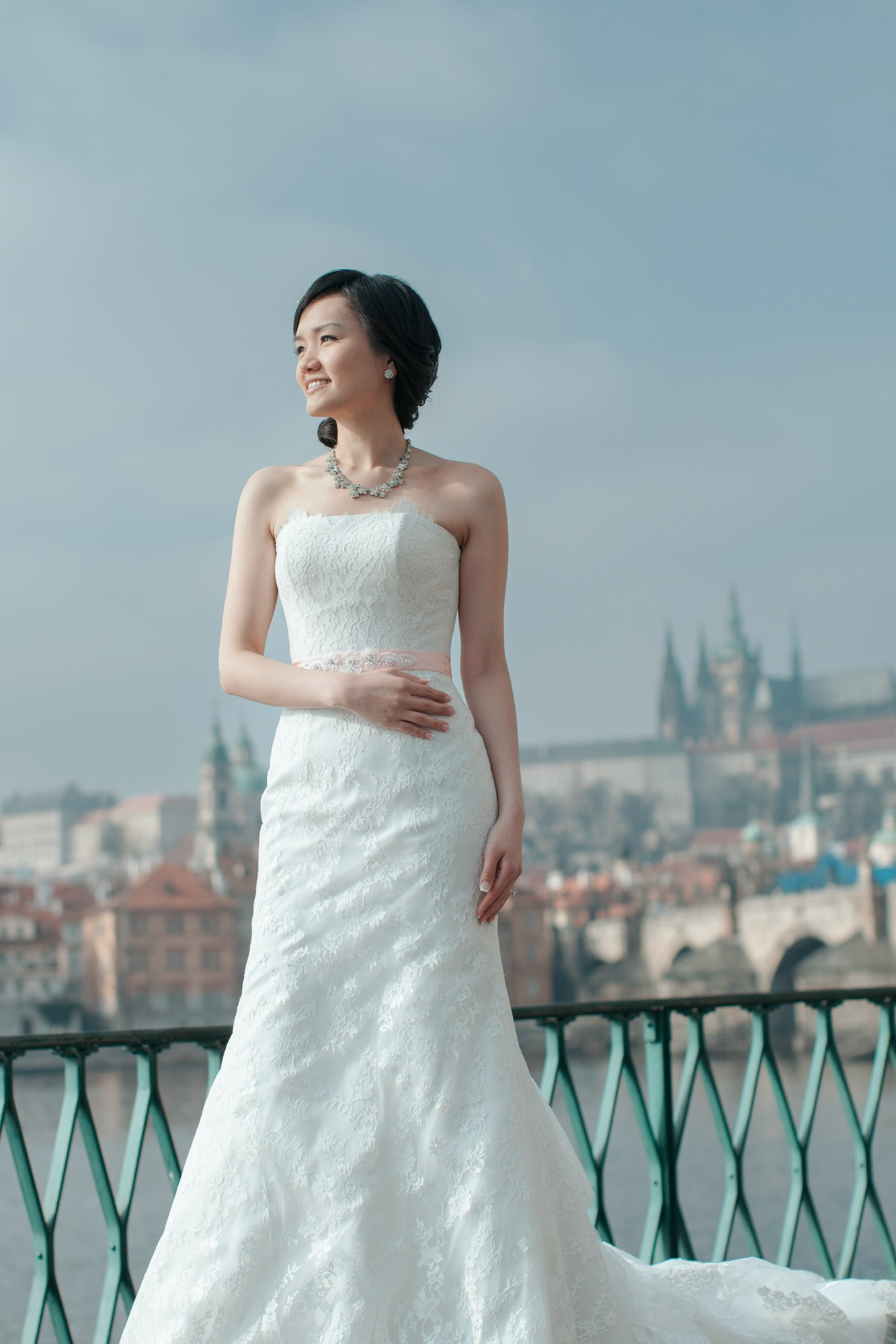 As the winter landscape of Prague is seen behind her, a Hong Kong bride poses for a portrait in the winter sunlight.