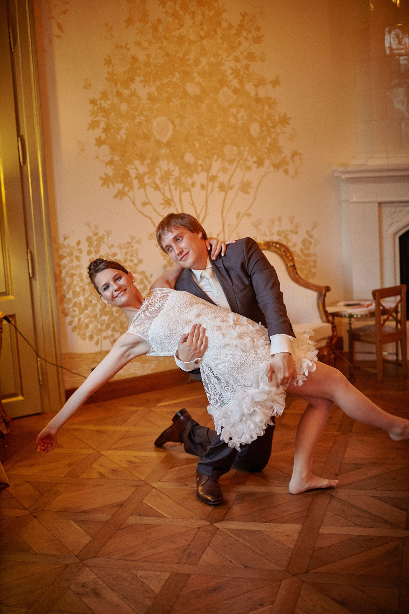 The groom, on bended knee, supports his beaming bride in a graceful dip at the conclusion of their first dance at Chateau Mcely.