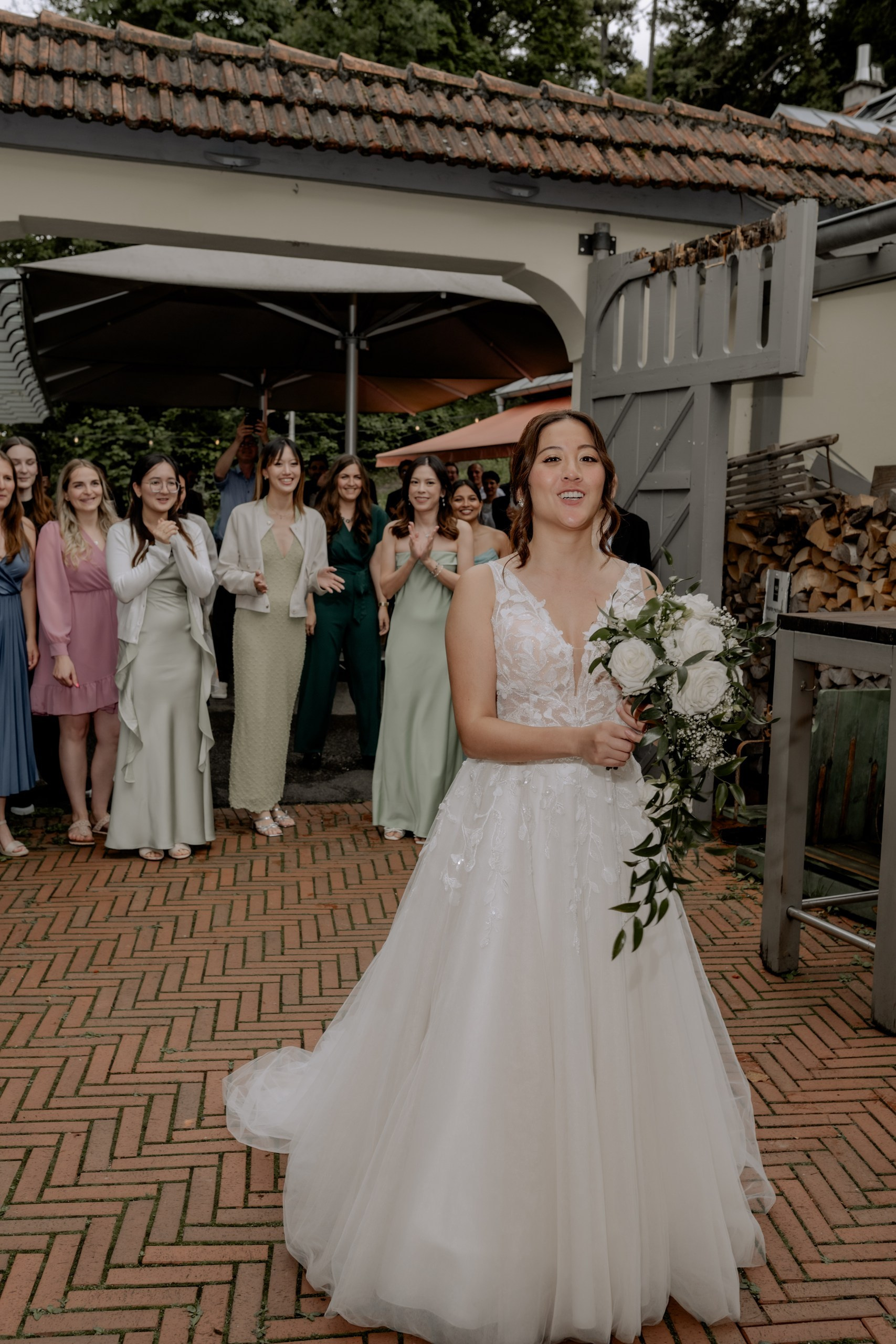 Die Braut sitzt lächelnd auf der Terrasse des Nikolaushofs, der Schleier leicht verweht, umgeben von herbstlichen Tönen und gemütlicher Atmosphäre.