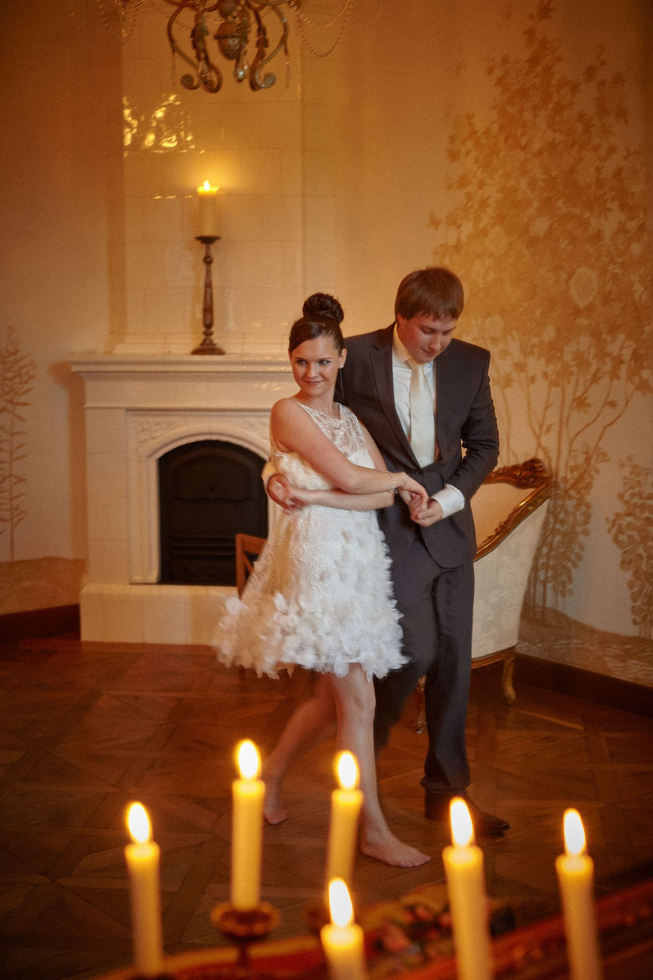 Newlyweds perform their imperfect waltz, captured in a candlelit mirror at the romantic Chateau Mcely.