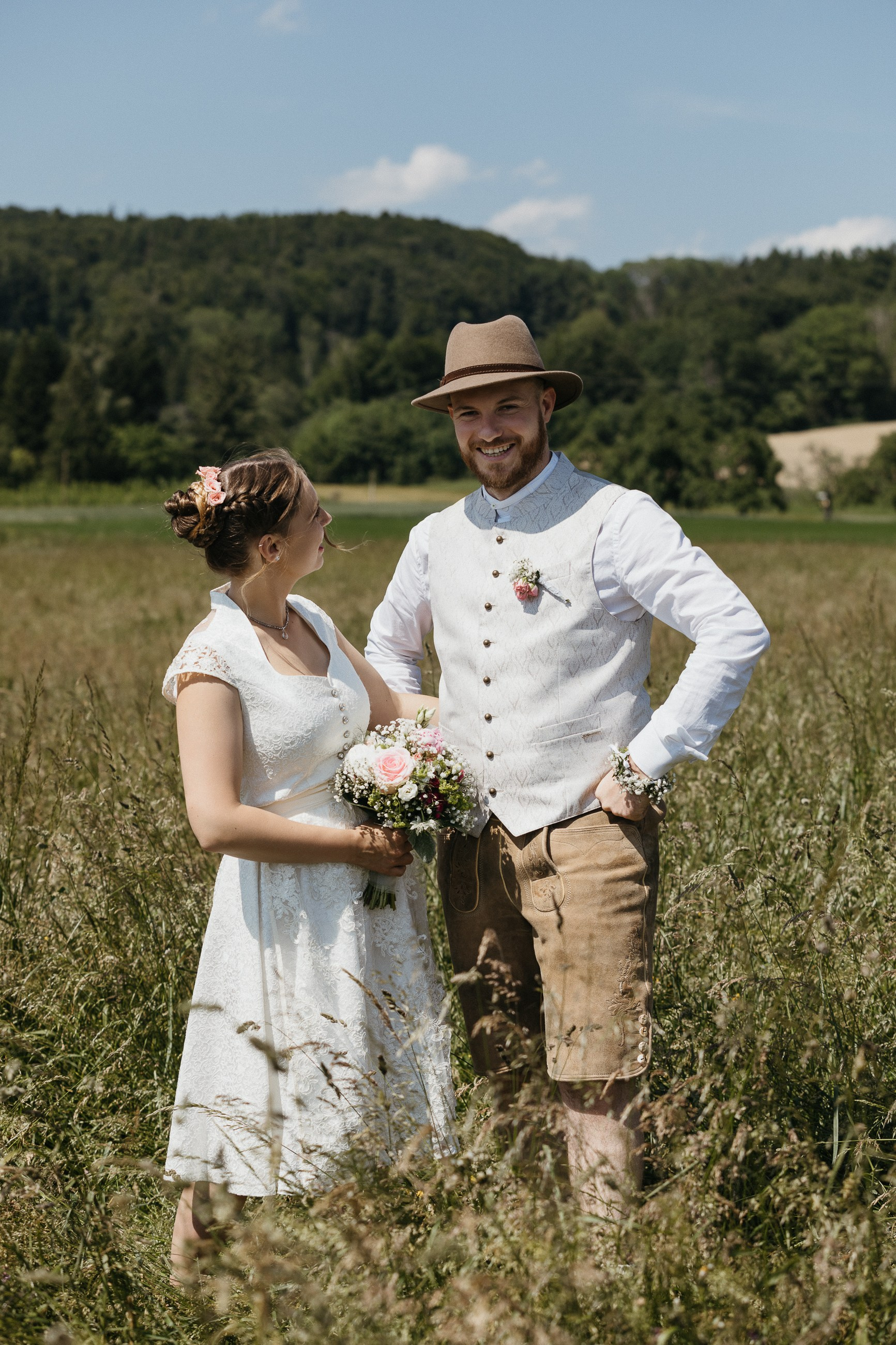 Hochzeitspaar posiert in sonniger Wiese, Süddeutschland