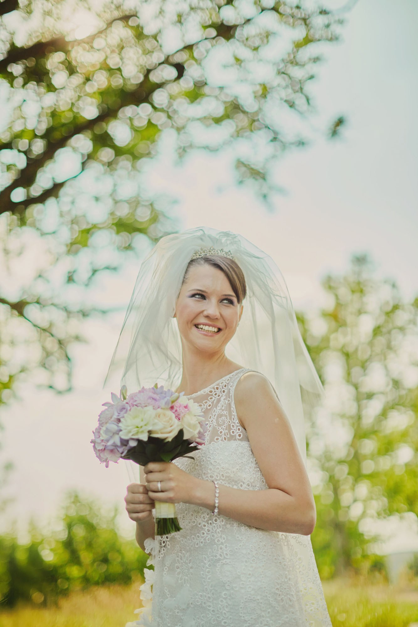 Bride with bouquet smiling on chateau grounds.