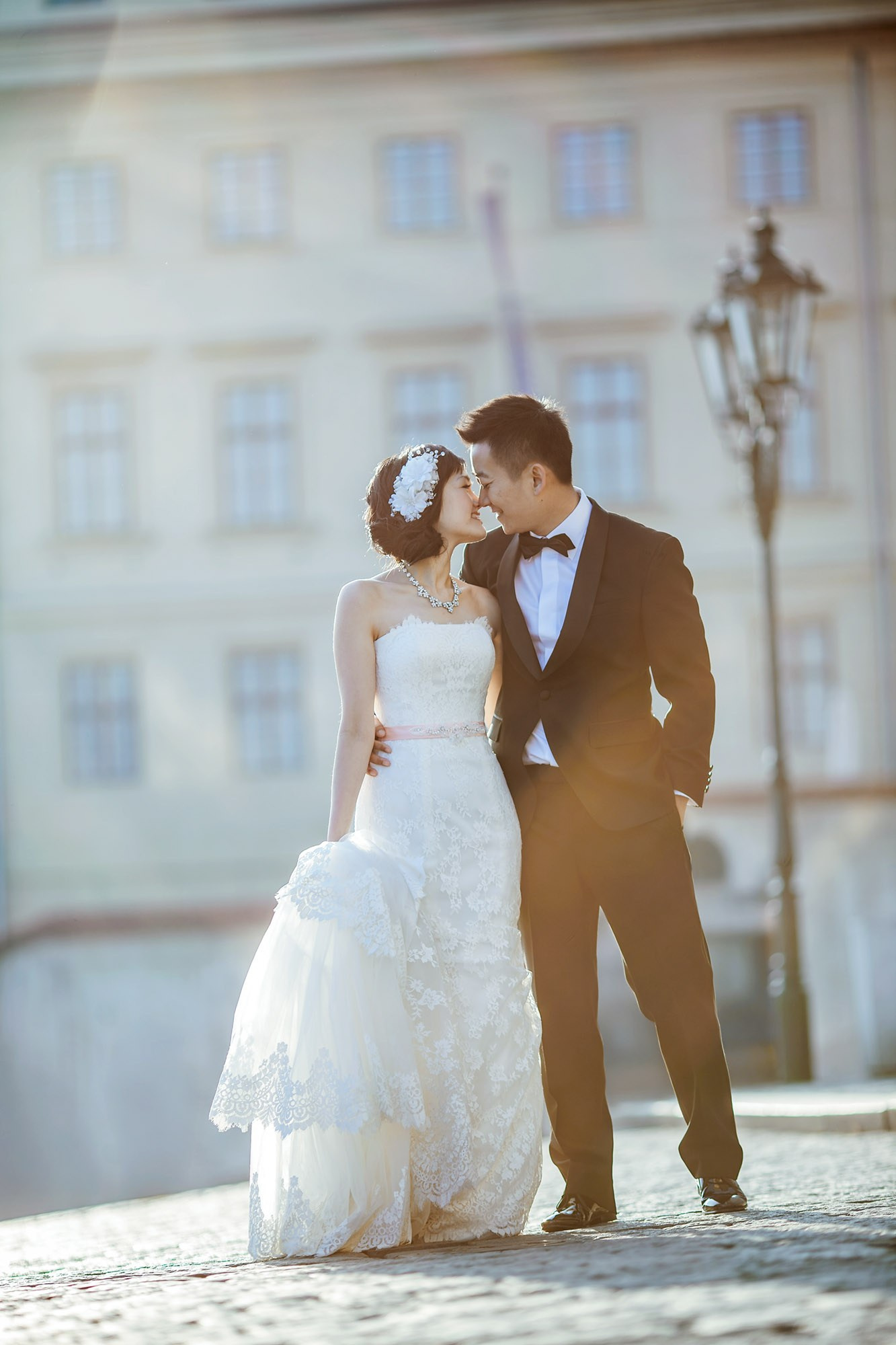 An elegantly dressed Hong Kong bride & groom kiss as they in the historic courtyard of Prague castle.