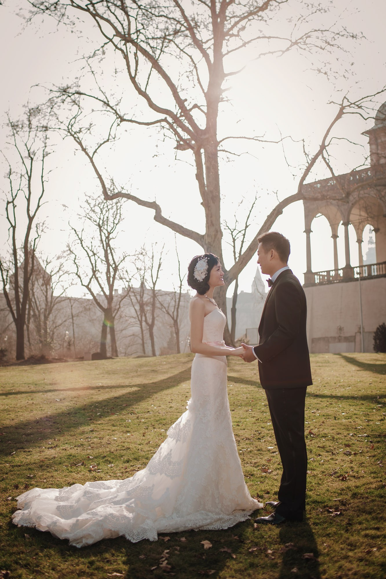 As the winter sunlight illuminates them from behind, a Hong Kong bride & groom explore the grounds of Prague's Queen Anne's Palace (Belvedere) during their love story photo session.
