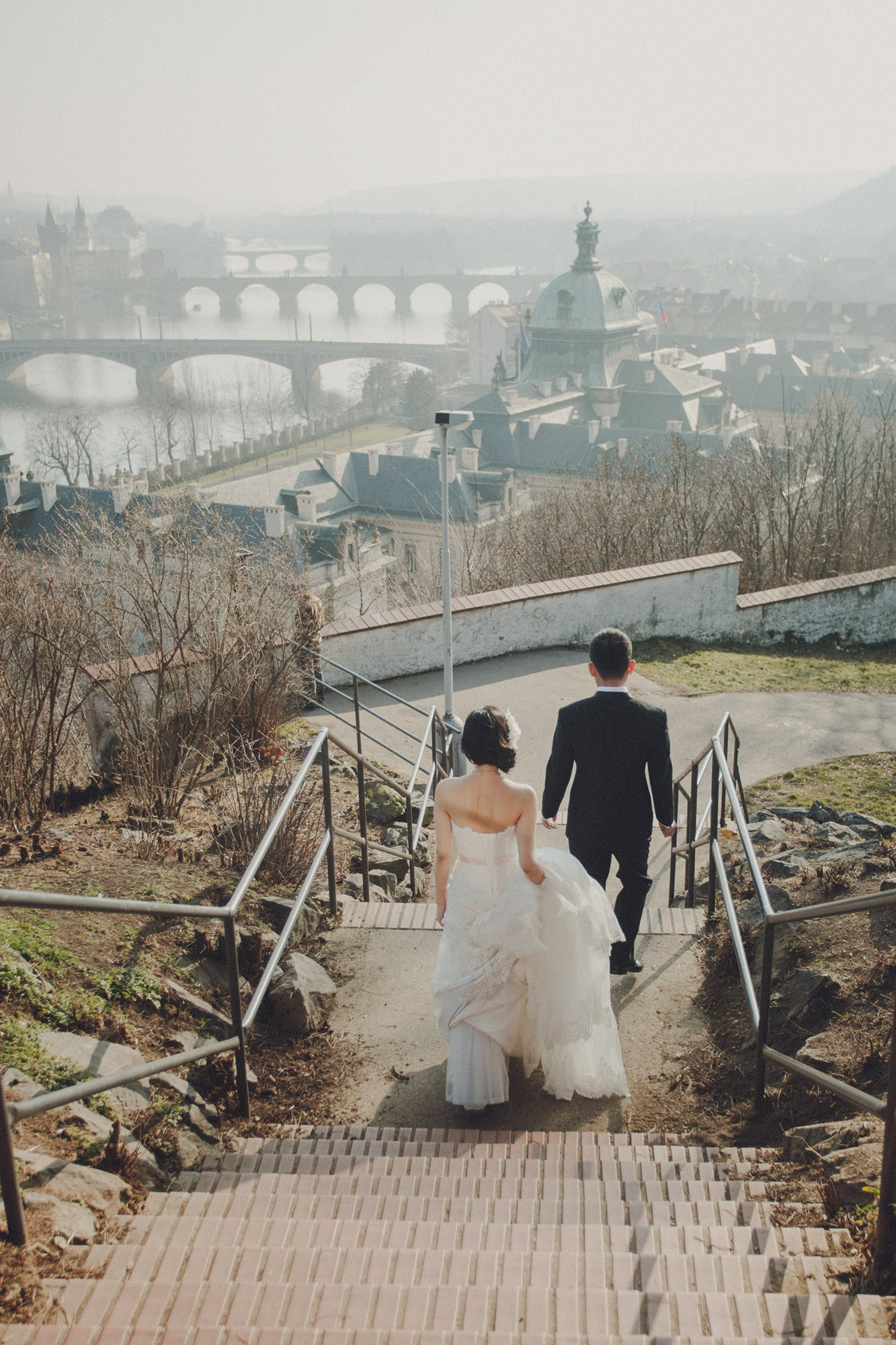 A stylish Hong Kong bride & groom explore the landscape of Prague from their vantage point overlooking the city on a winter day.