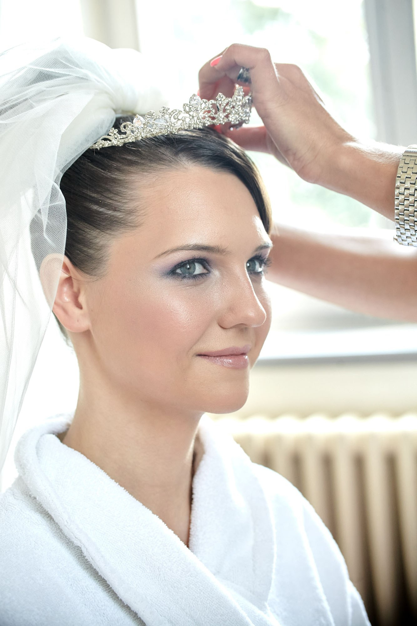 Bridal preparation at Chateau Mcely: Hair and makeup artist helping place the tiara on the bride.