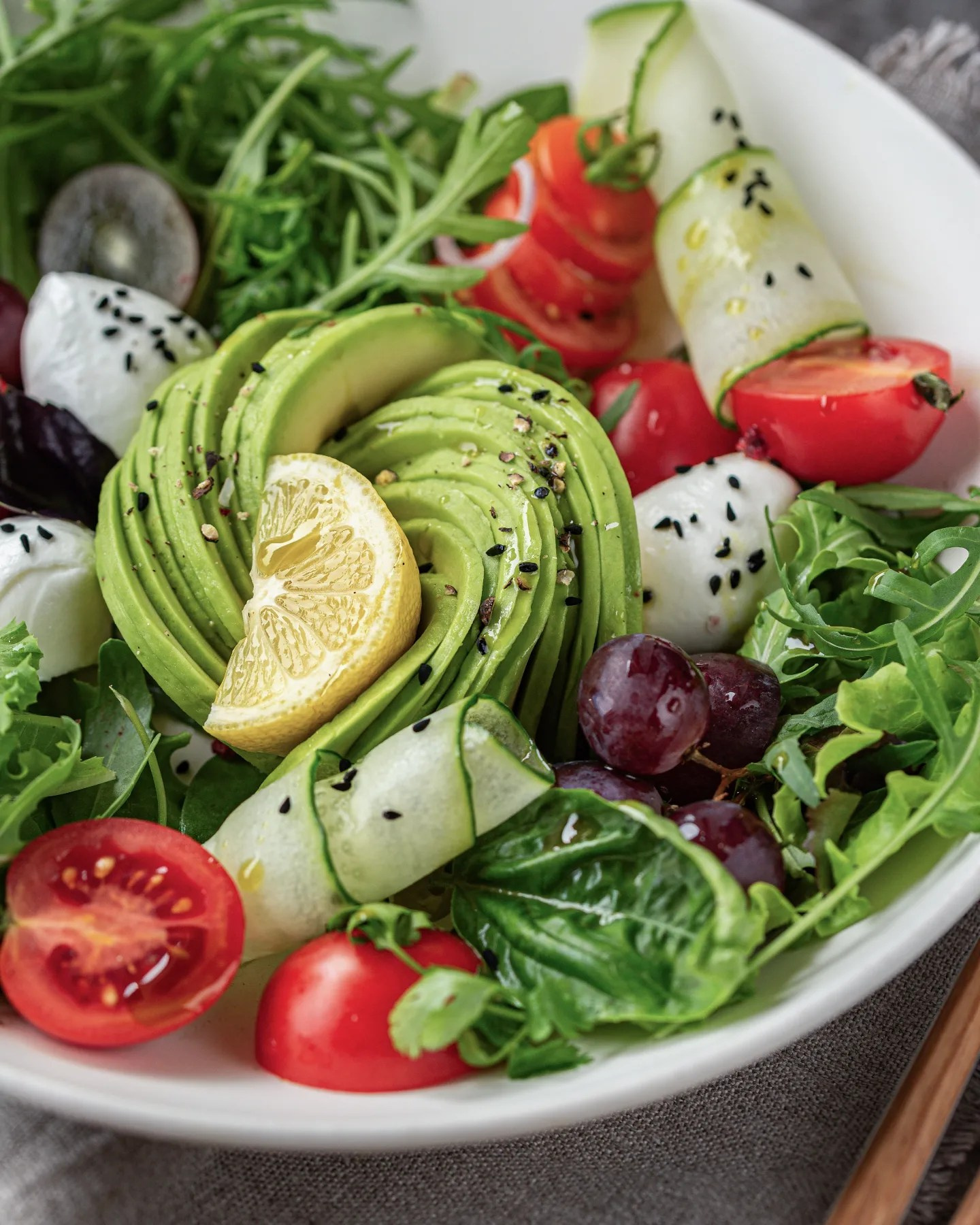 ein Teller mit einem gestyltem Gemüsesalat aus Avocado, Gurke, Tomate und Mozzarella